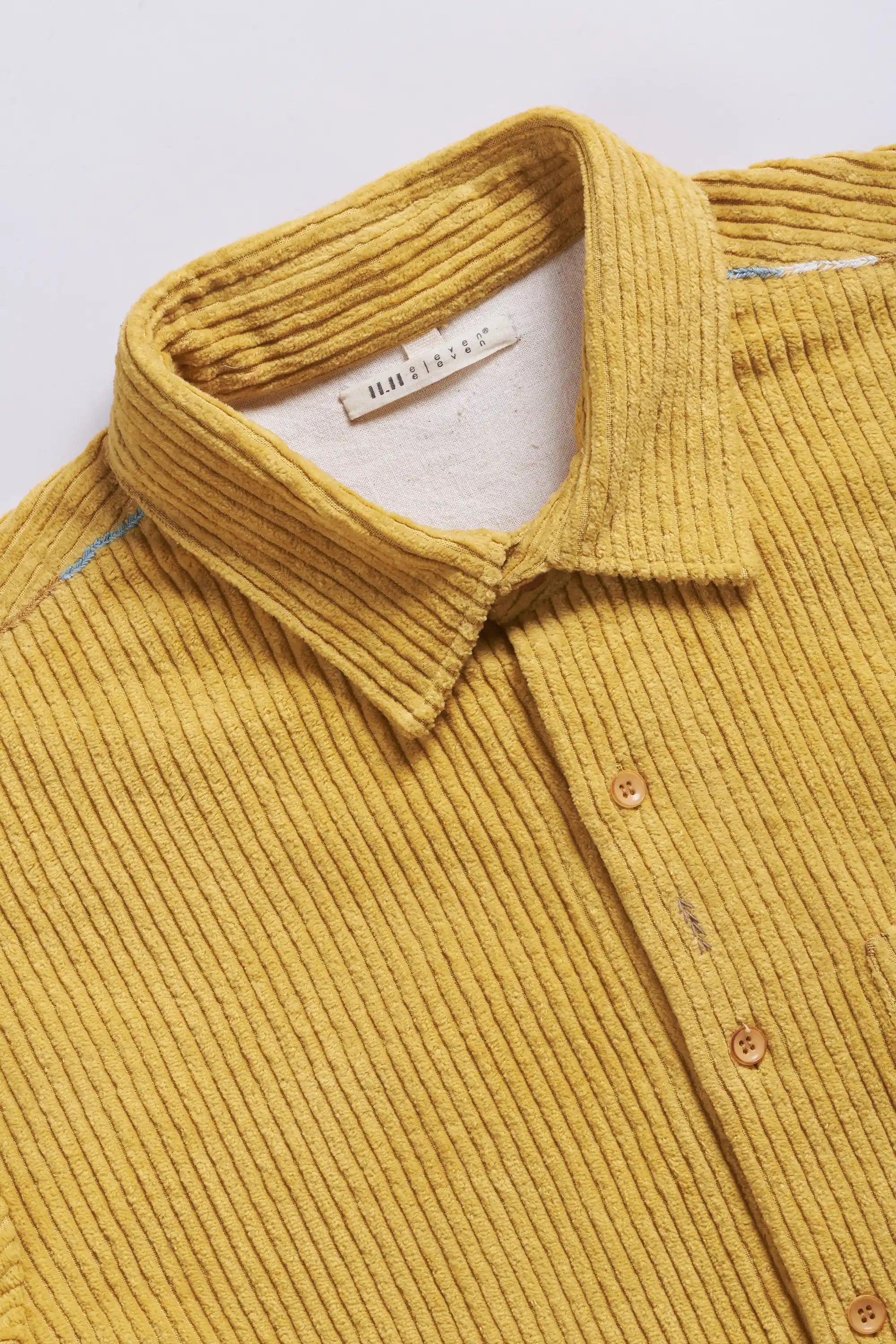 Yellow corduroy shirt with collar and buttons on a light grey background