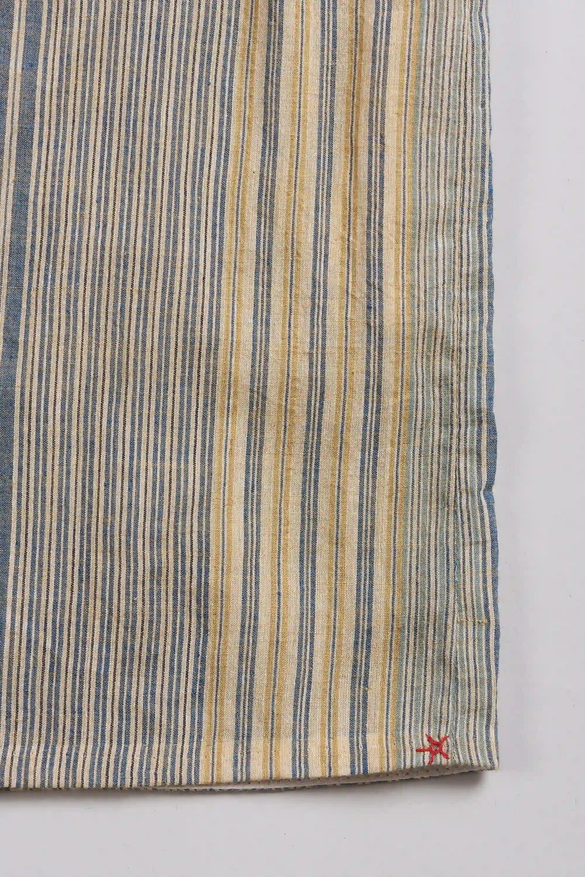 A close-up of a striped textile, likely a kimono or sarong, with a small red star detail near the bottom right corner.