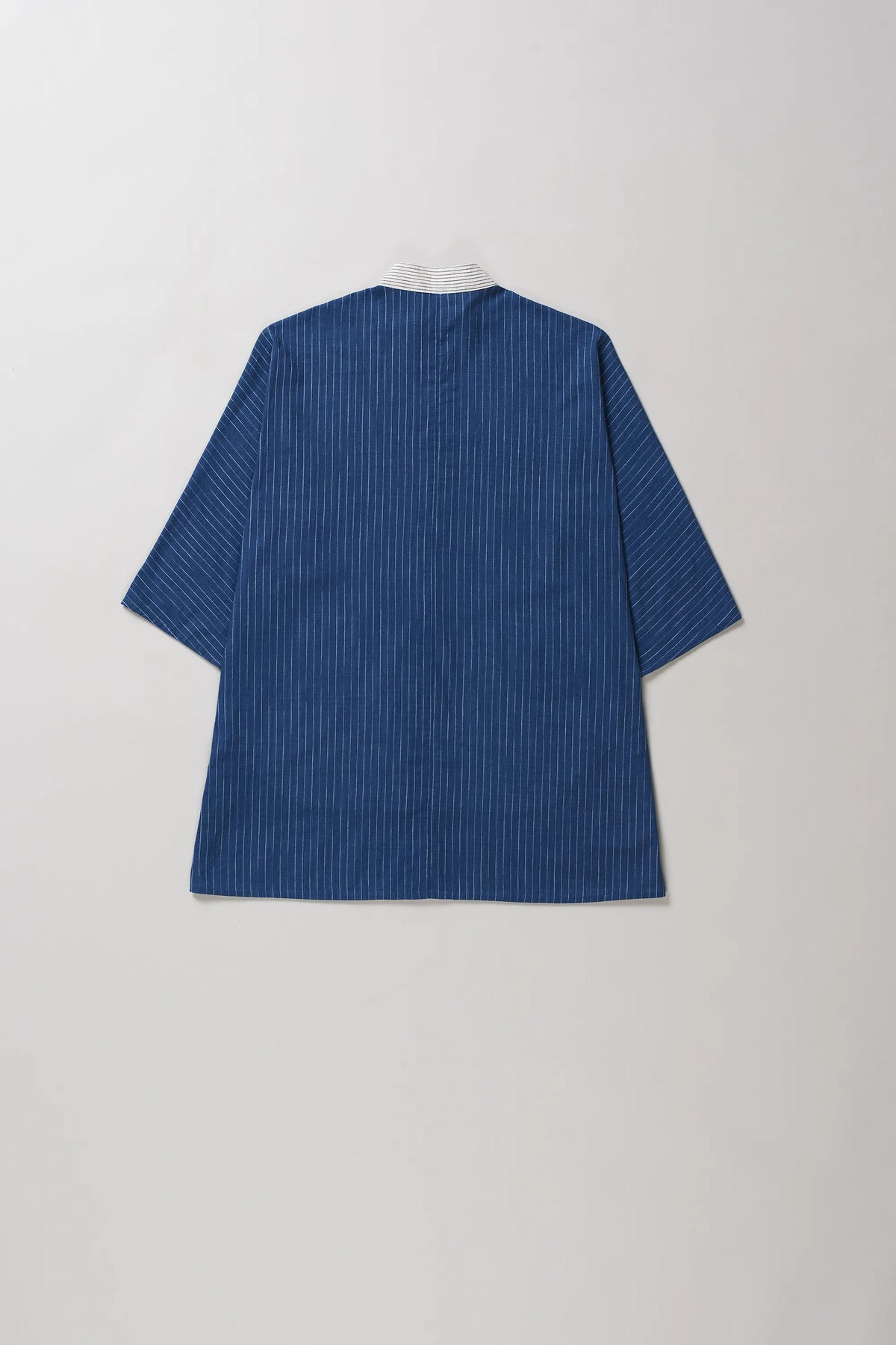 Back shot of indigo short-sleeve shirt with fine vertical pinstripes, shown from the back against a light grey background.