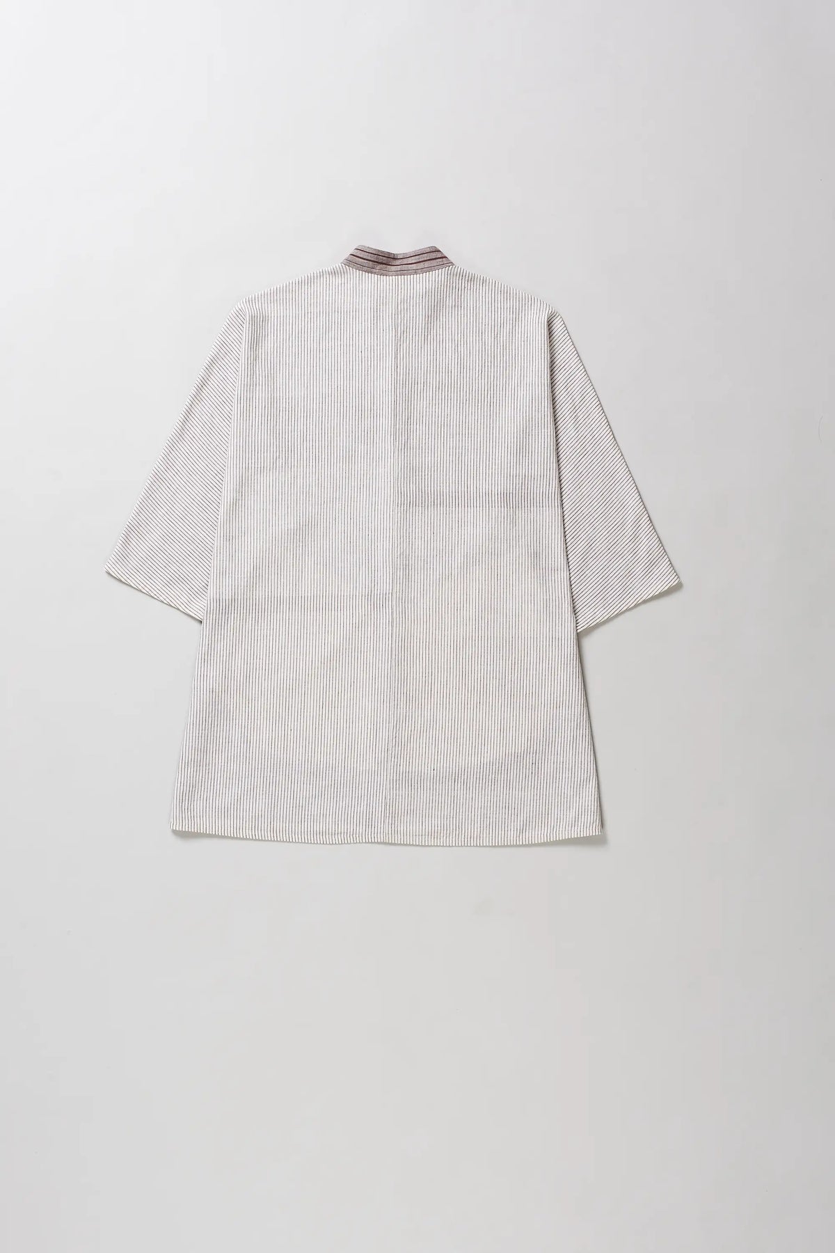 A light beige textured shirt with three-quarter sleeves and a high collar, shown from the back on a neutral light grey background.