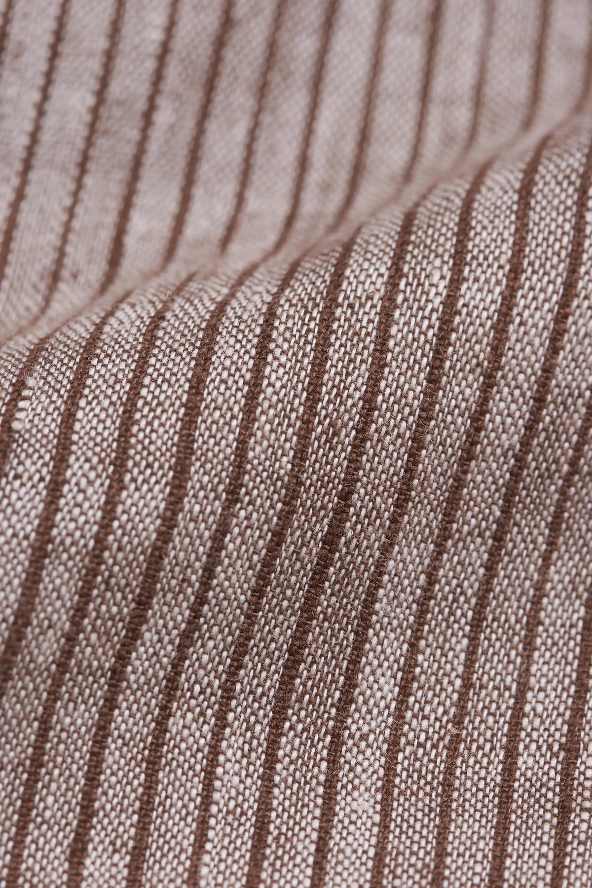 Close-up of a woven fabric with vertical brown stripes on a warm taupe-beige background.
