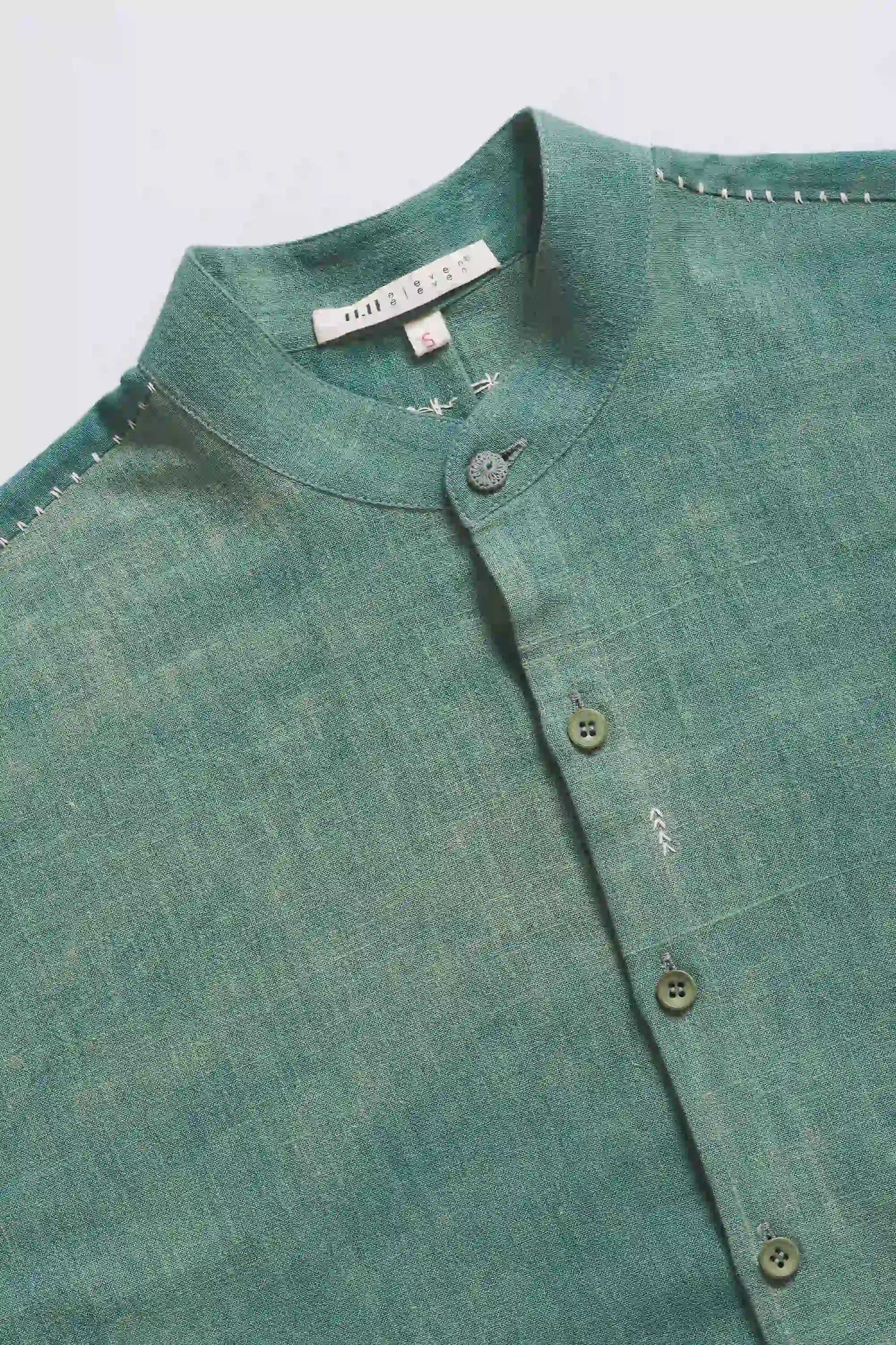 Close-up of a green shirt with buttons on a light grey background