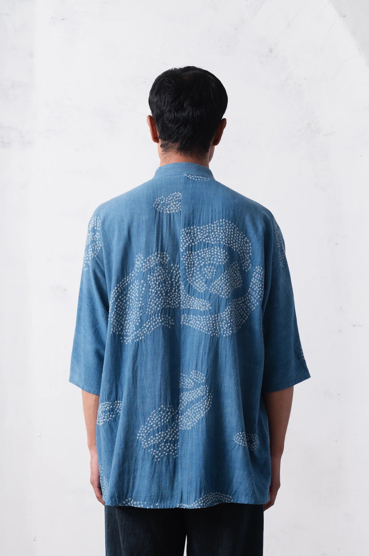 Person wearing a blue cotton shirt with bandhani on a light grey background