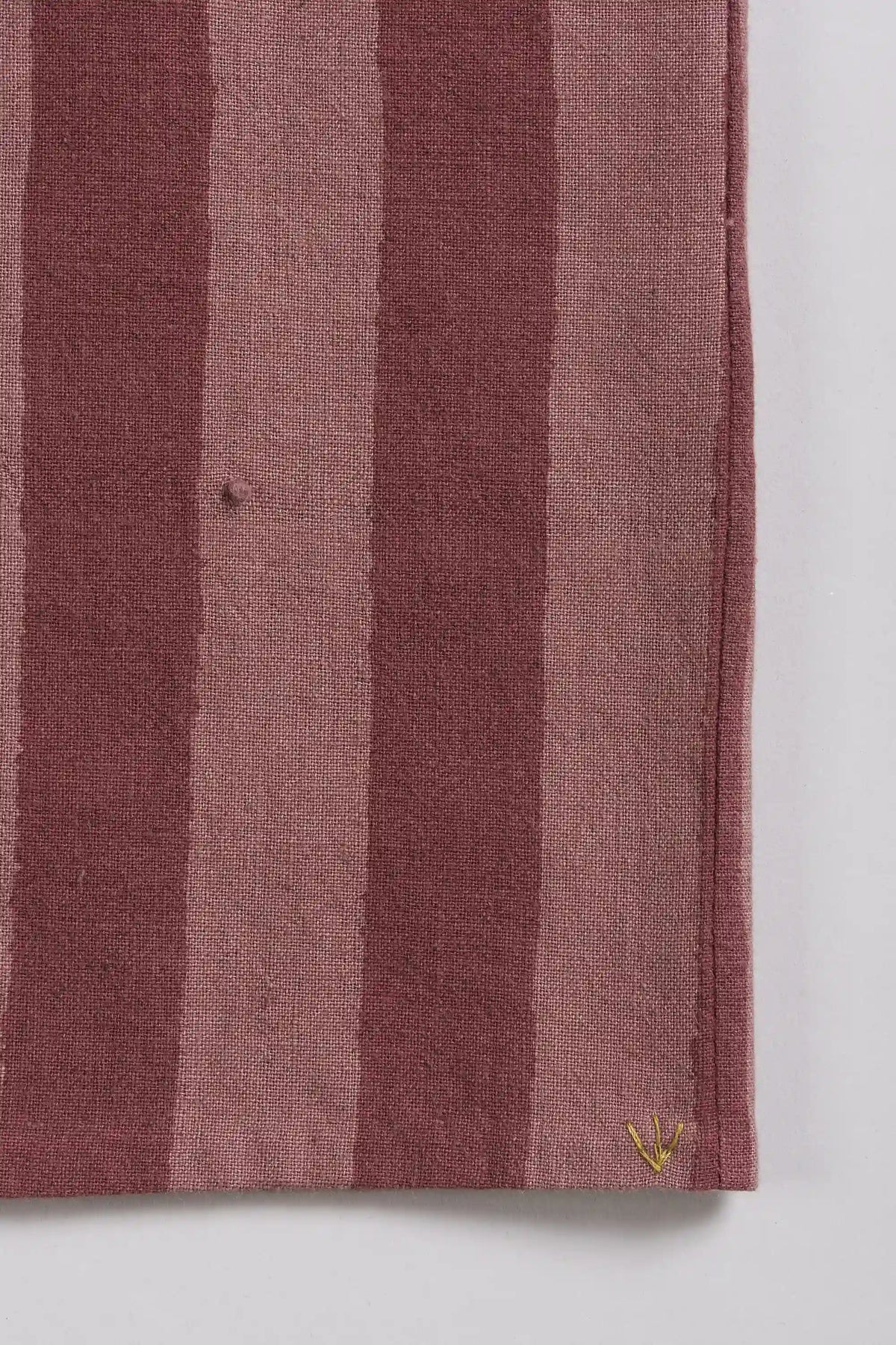 A close-up of a striped, a small yellow embroidered logo.