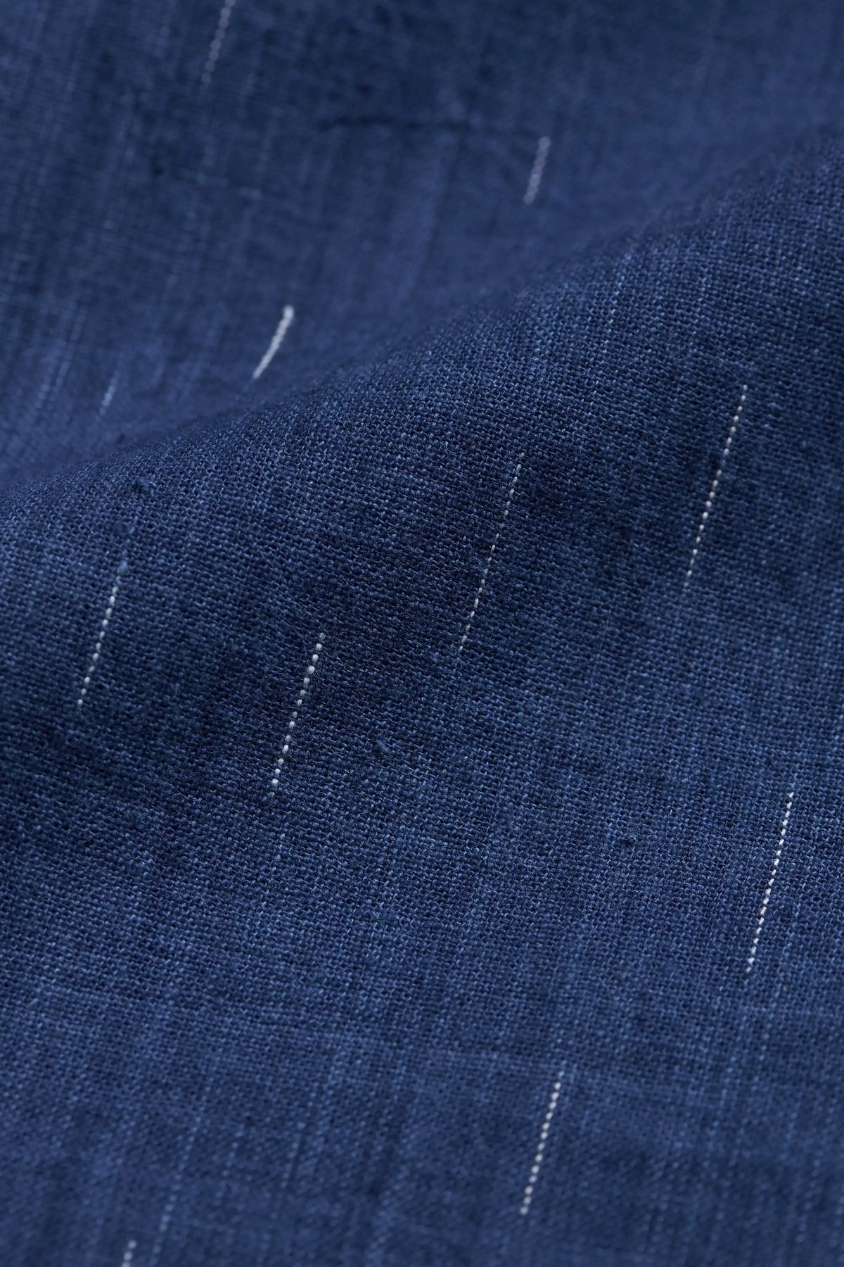 A close-up of fabric with a subtle woven texture and small scattered white thread-like accents.