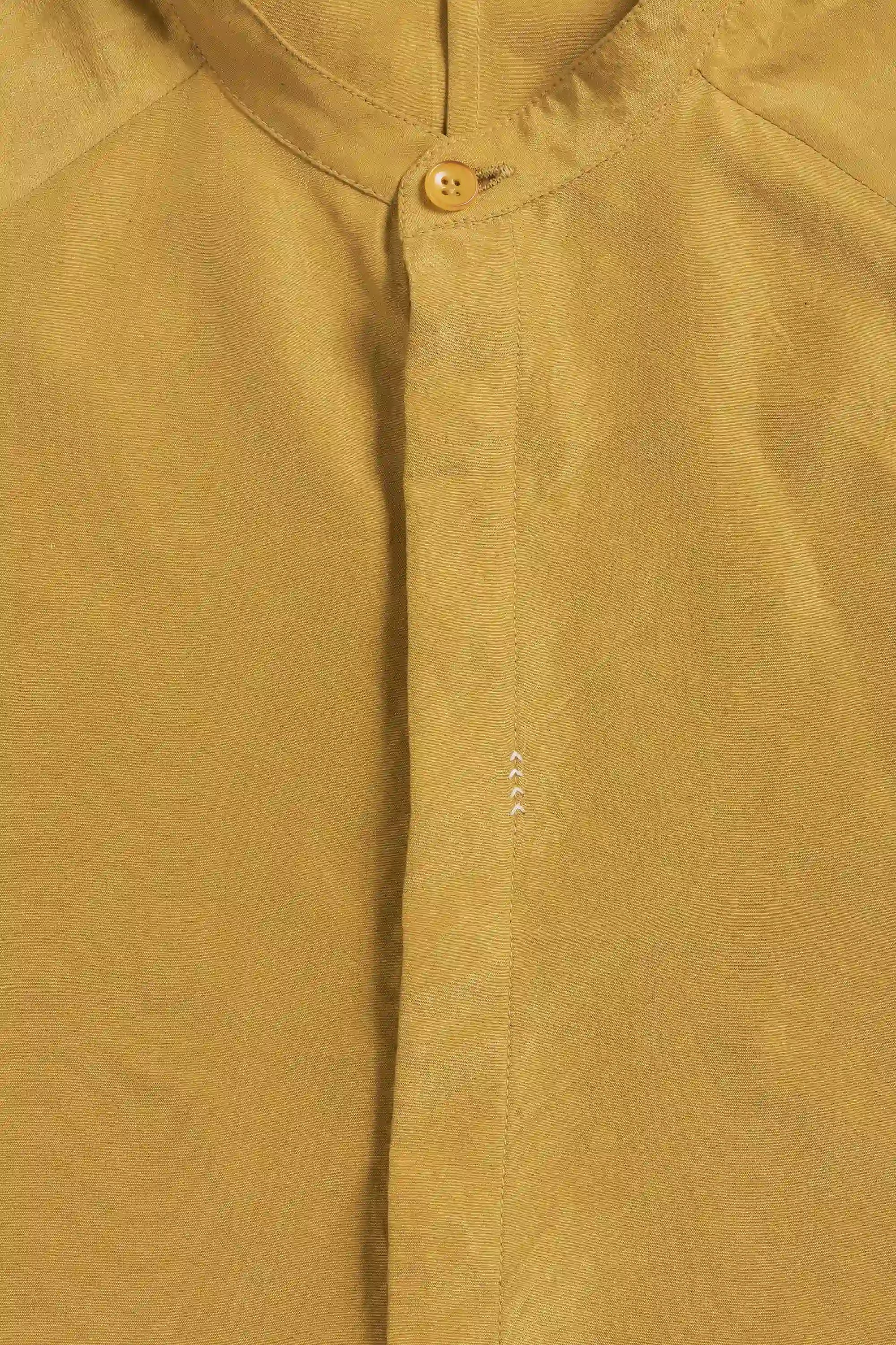 Close-up of a ochre yellow shirt with a button detail