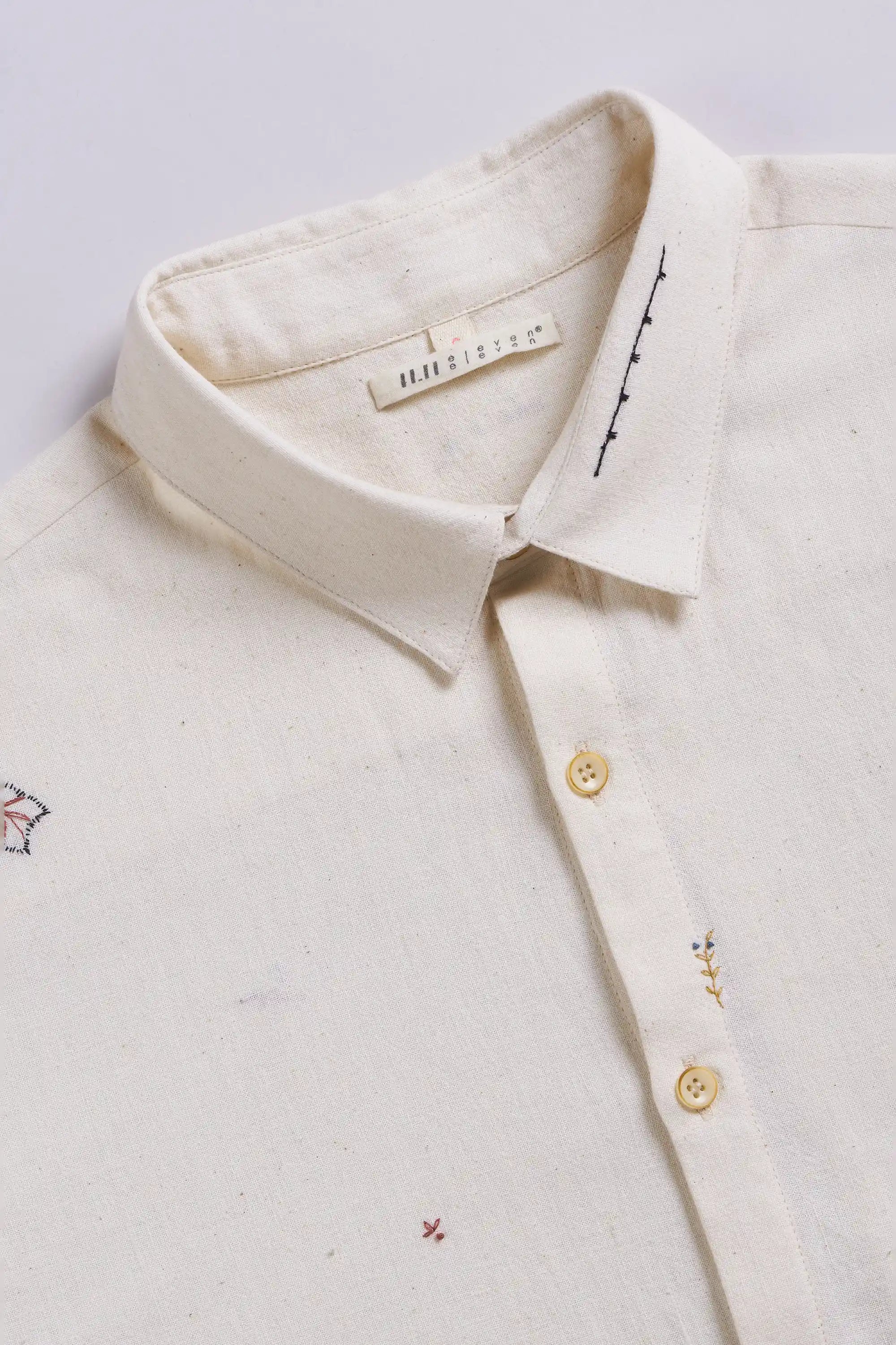 Close-up of a shirt with hand embroidery on a light grey background