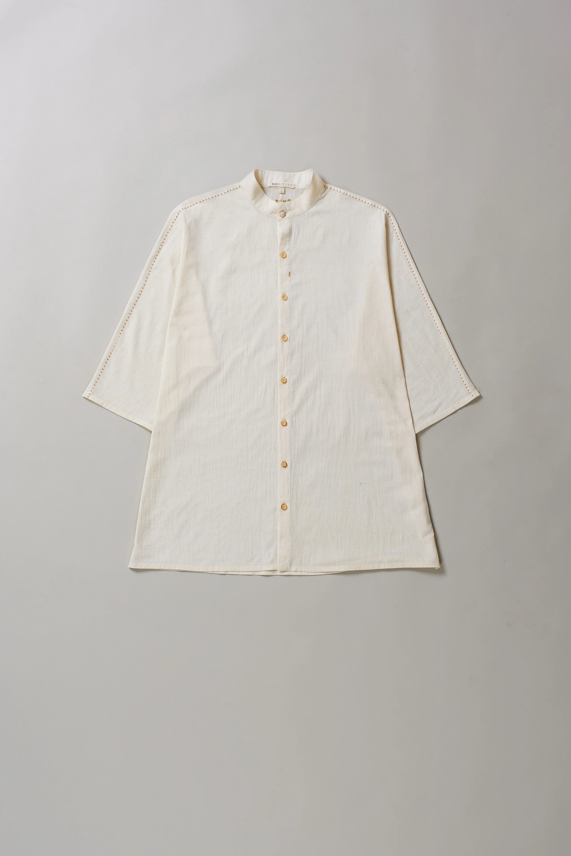 Ecru cotton shirt with buttons on a grey background