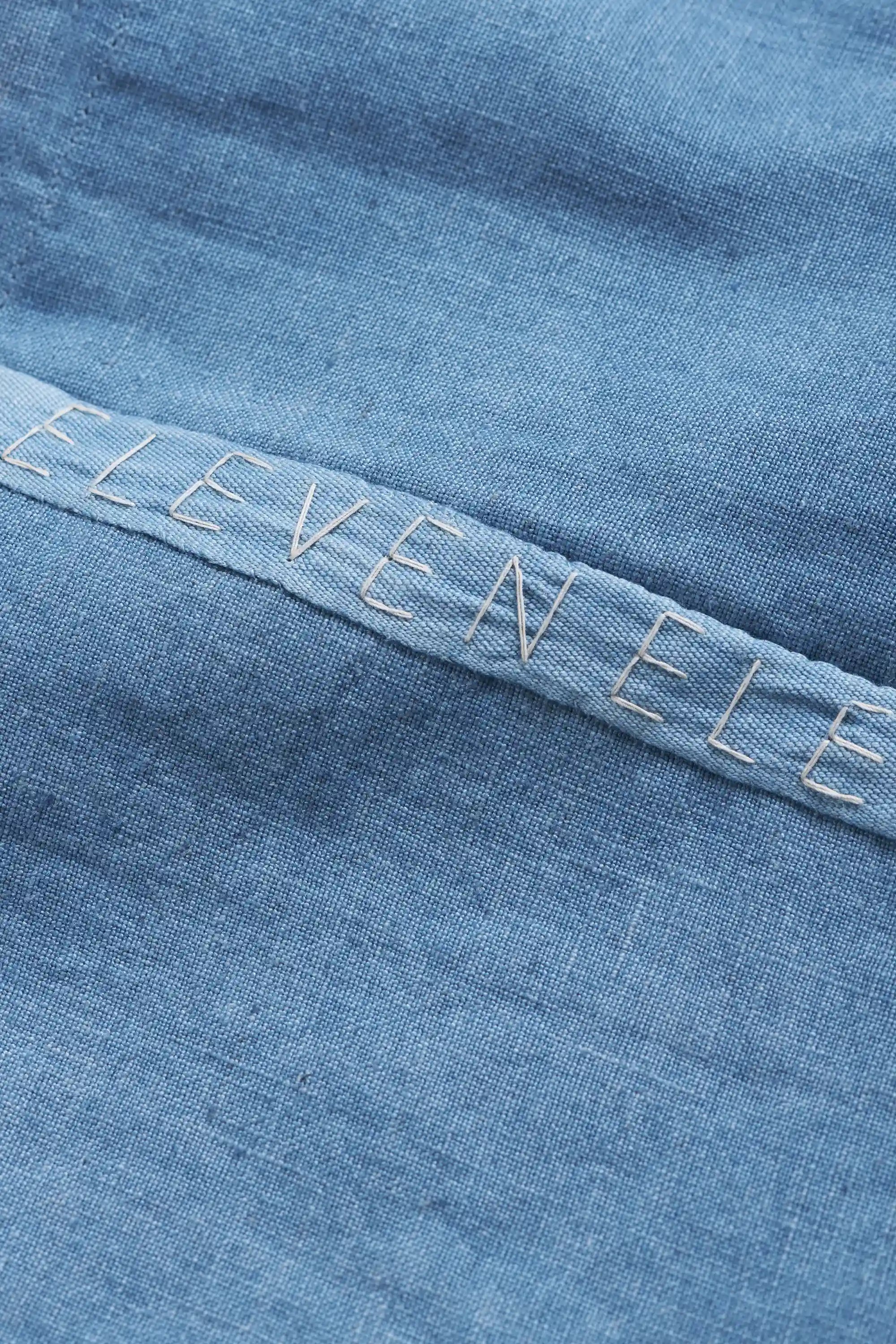 Close-up of blue fabric with 'ELEVEN' embroidered on it