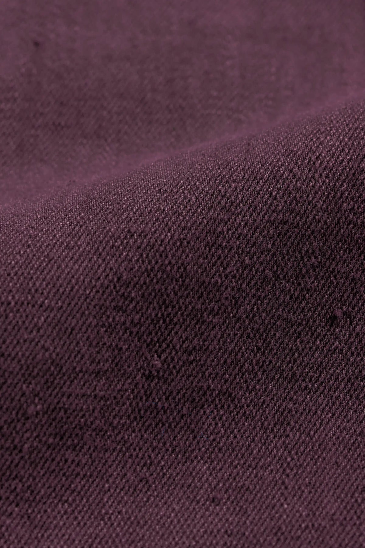 A close-up of fabric in a purple red color, showing the weave and soft folds.