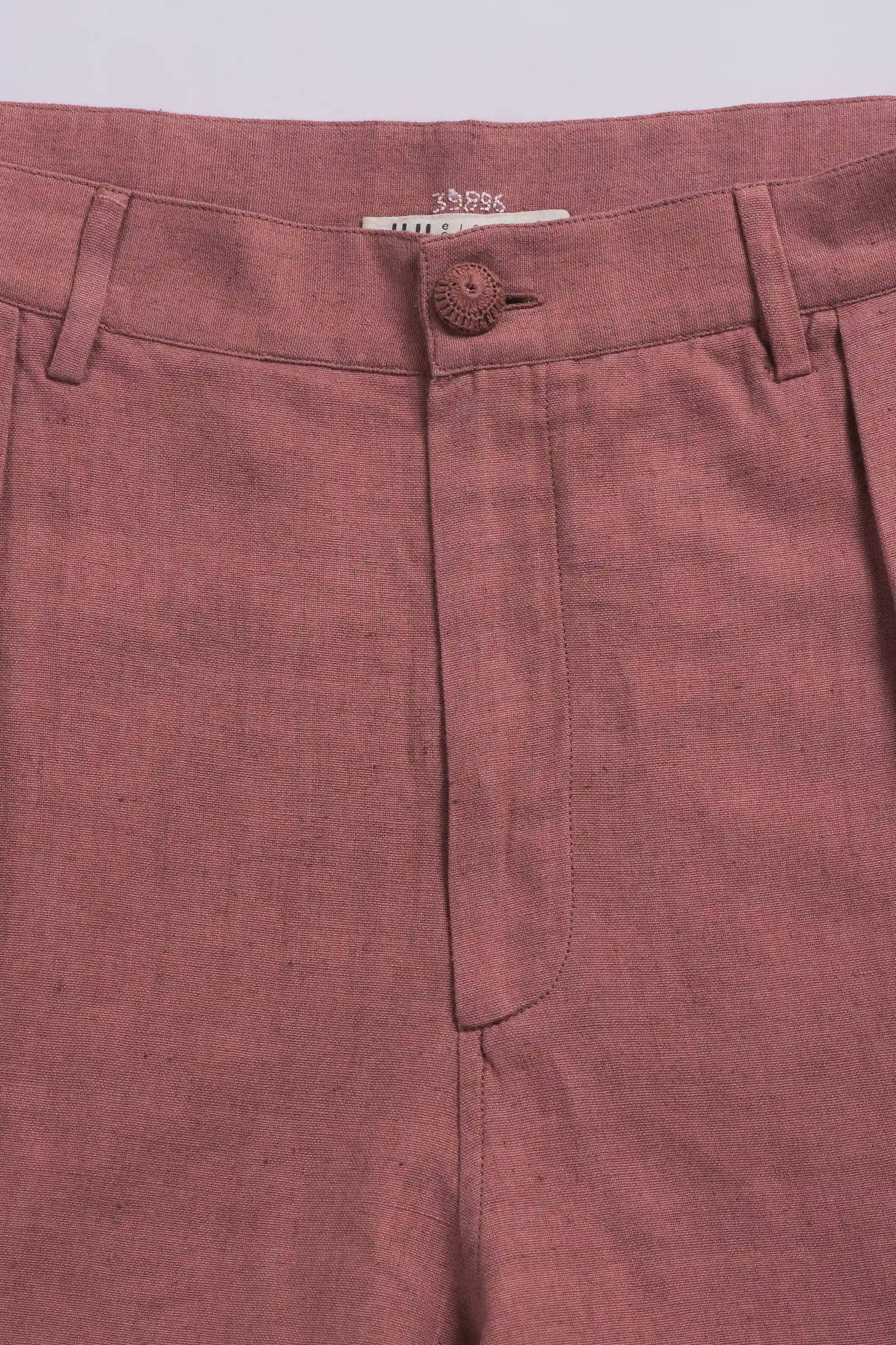 Close-up of pants with a button and label on a light grey background