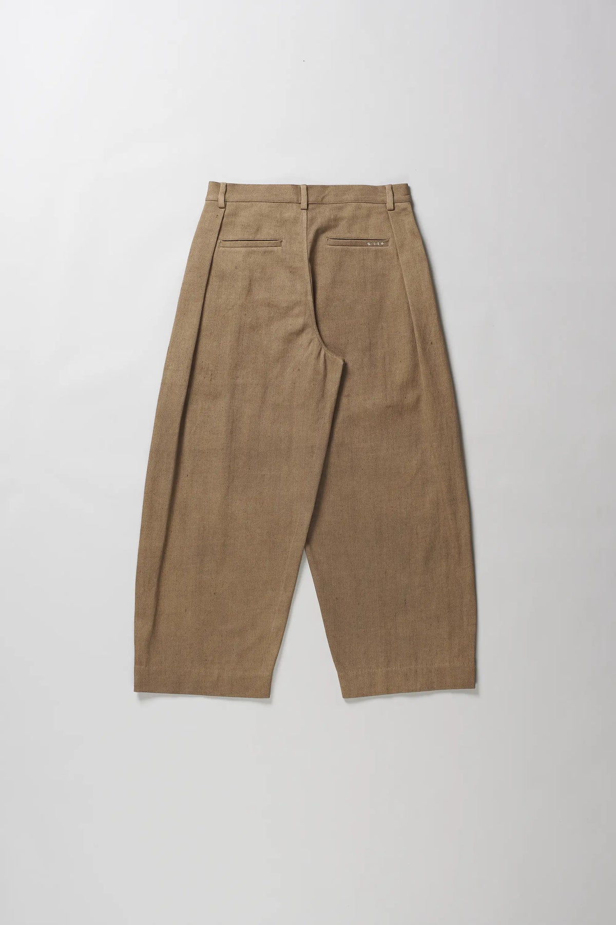 A pair of brown pleated trousers shown from the back, laid flat on a light grey background.