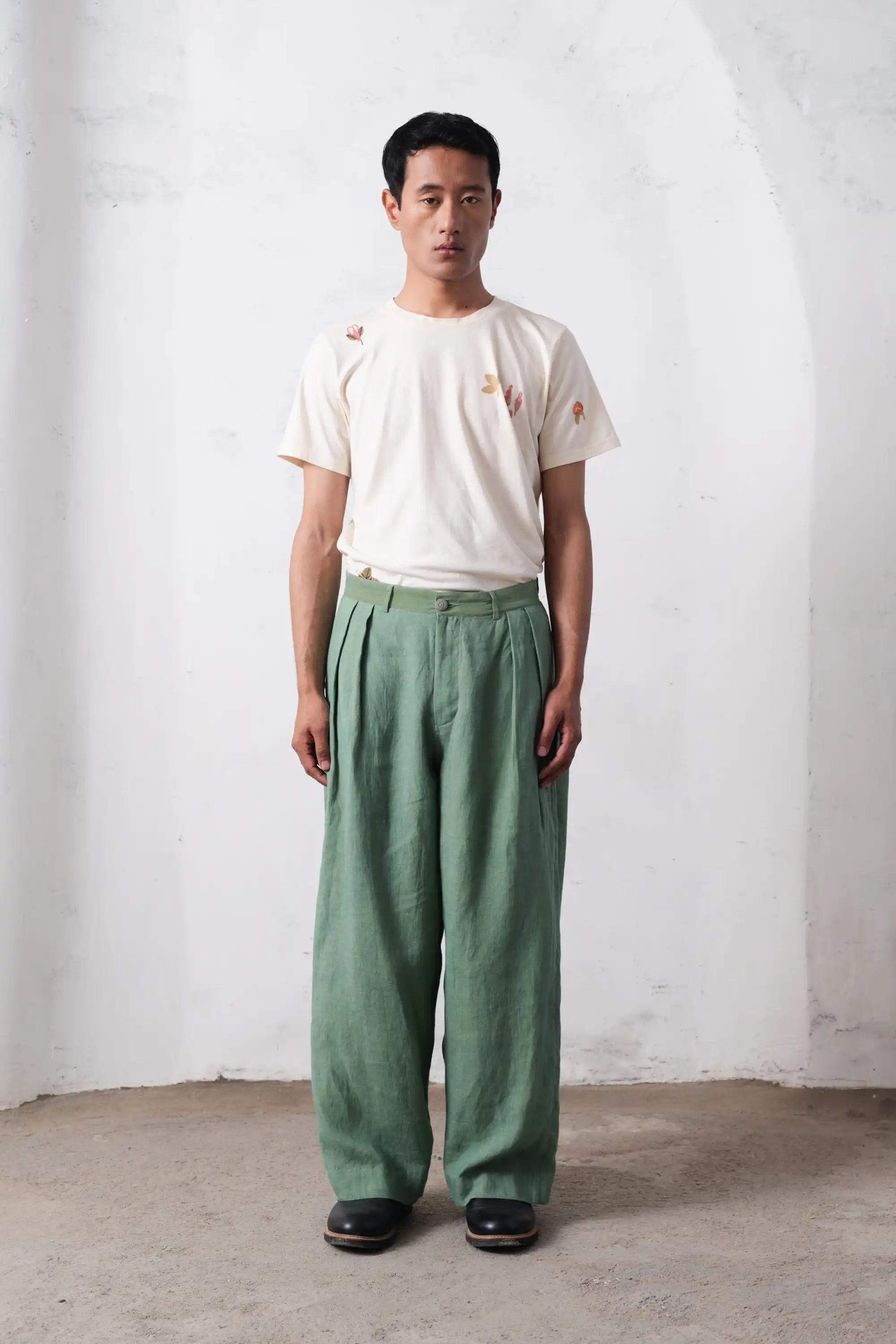 A man wearing turf green pleated pant