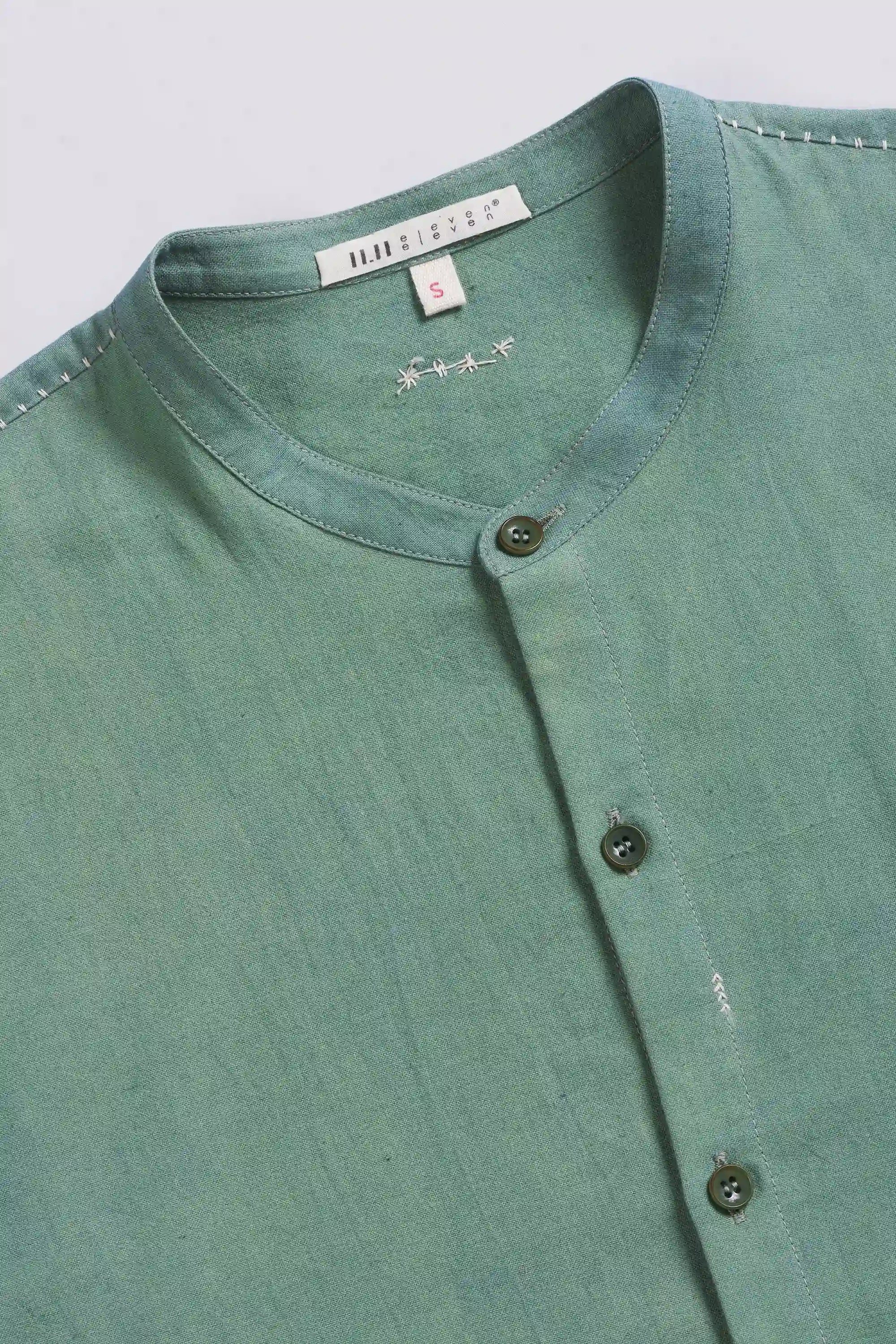 Green shirt with buttons on a light grey background