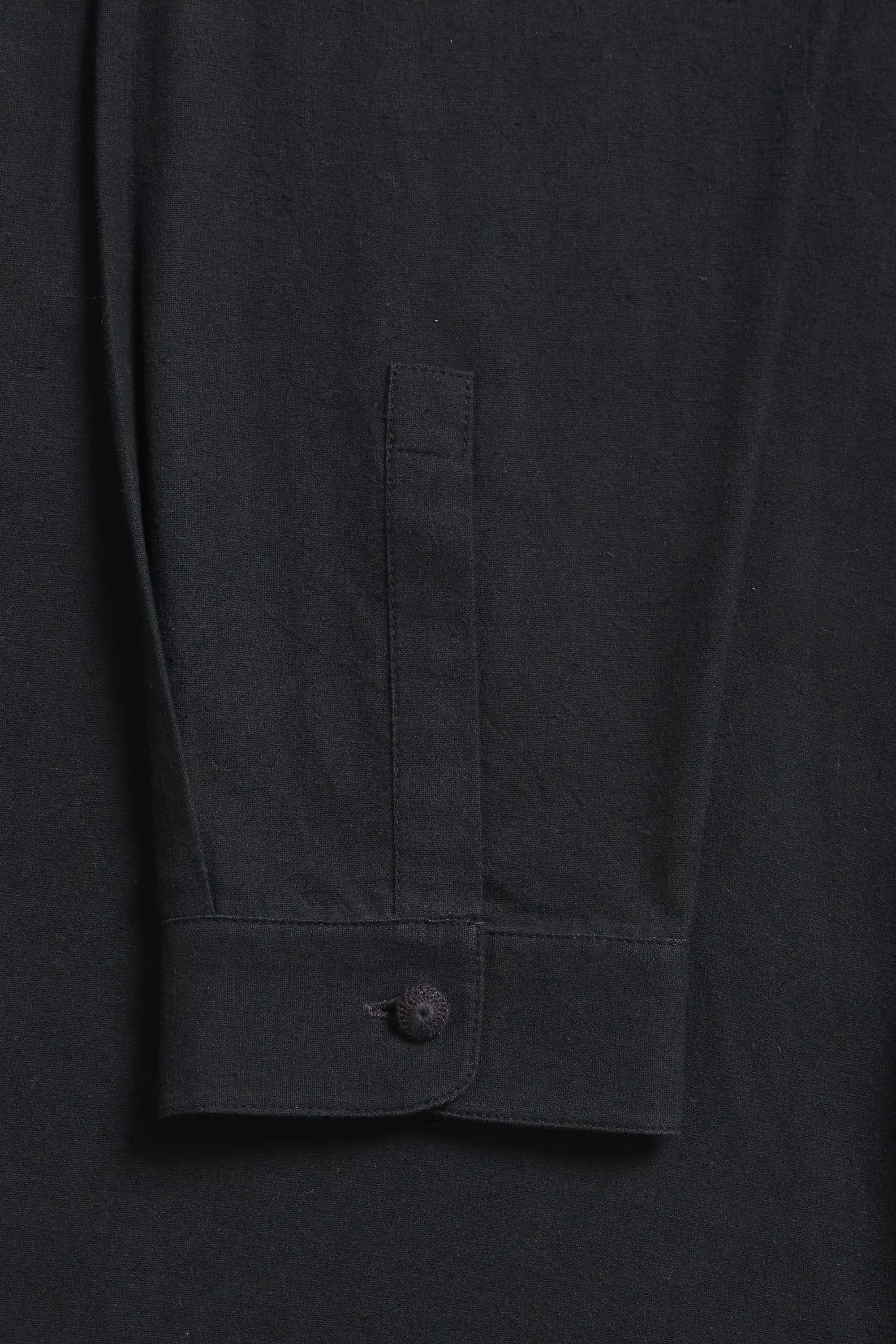 Close-up of a black shirt with a button and sleeve