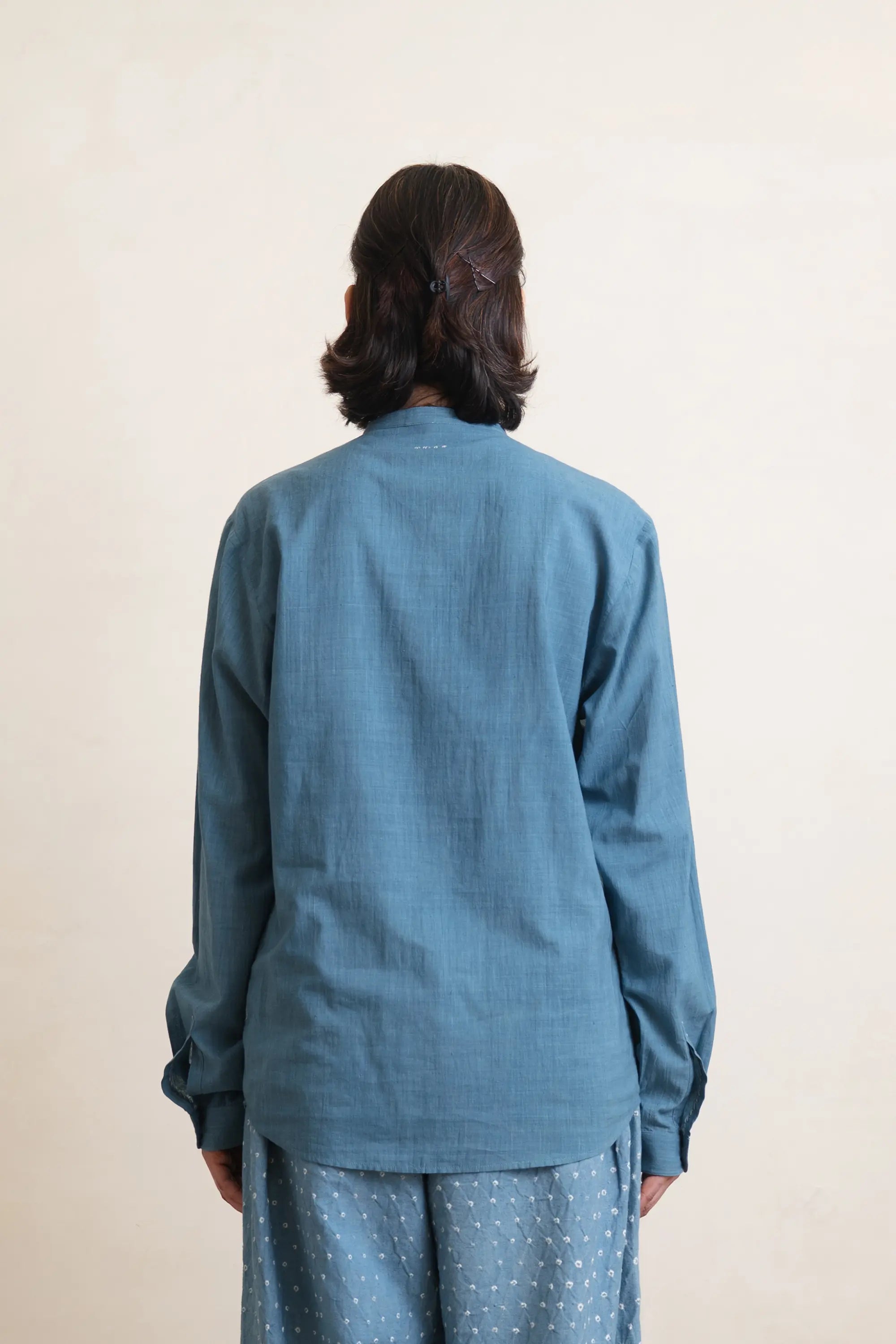 Person wearing a blue shirt and pants against a plain background