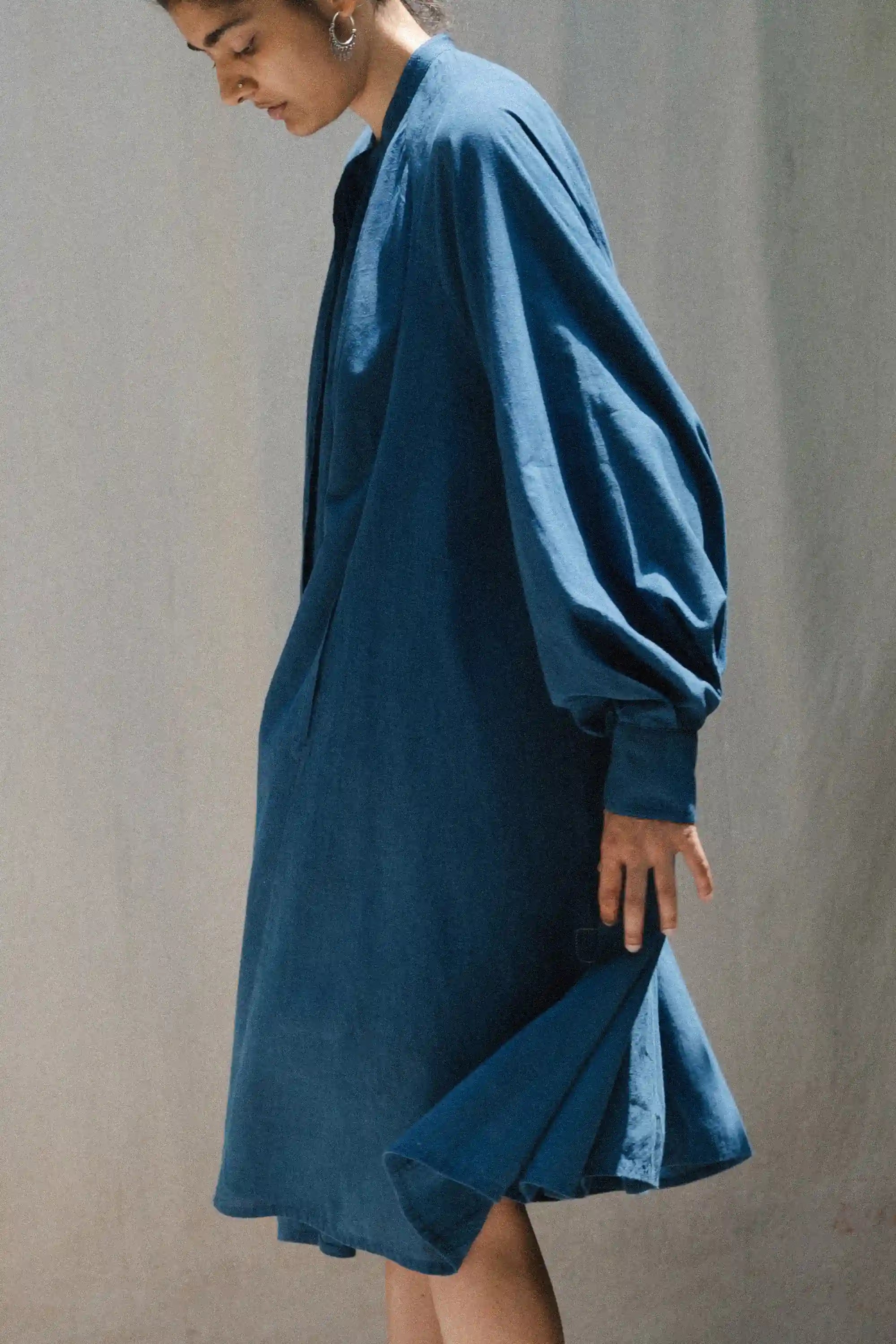 Person wearing a blue dress against a plain background
