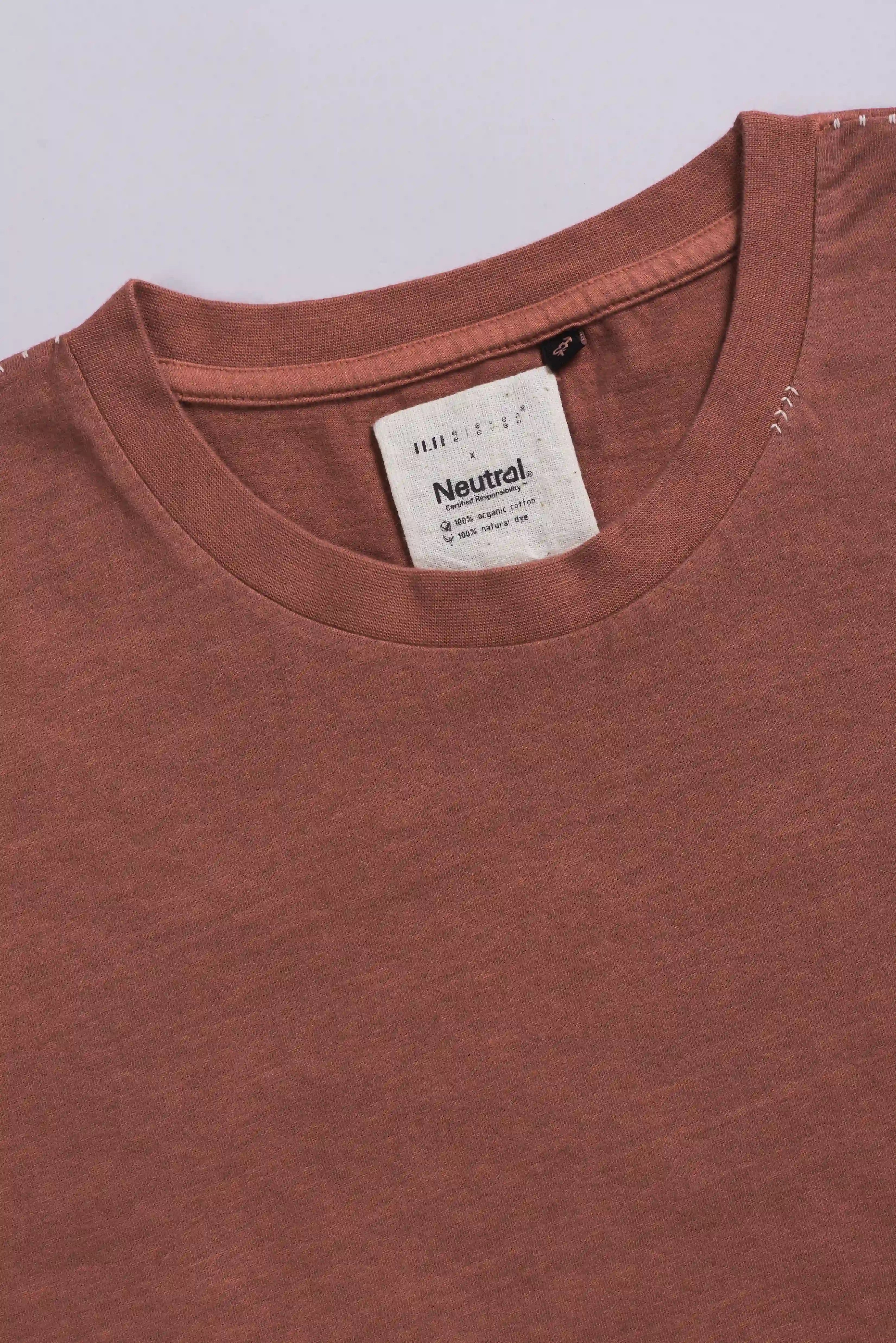Close-up of a orange rust t-shirt on a light grey background