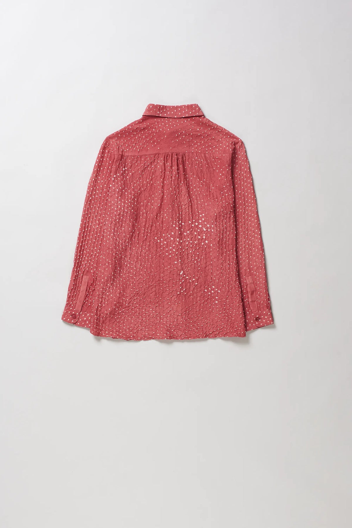 A pink wood long-sleeve shirt with a bandhani, speckled pattern, laid flat against a light grey background.