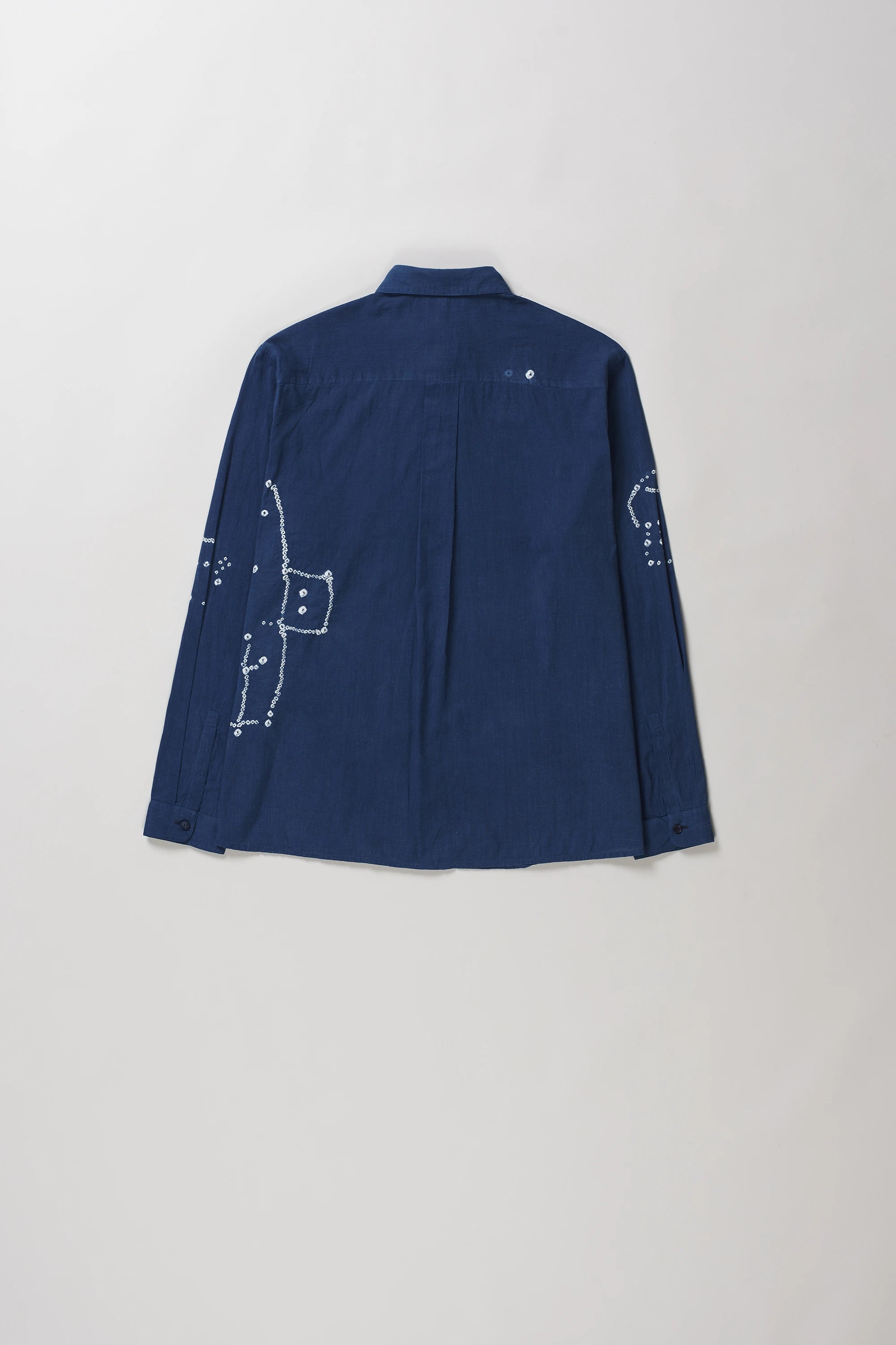 Back shot of medium indigo long-sleeve button-up shirt with bandhani, laid flat against a light grey background.