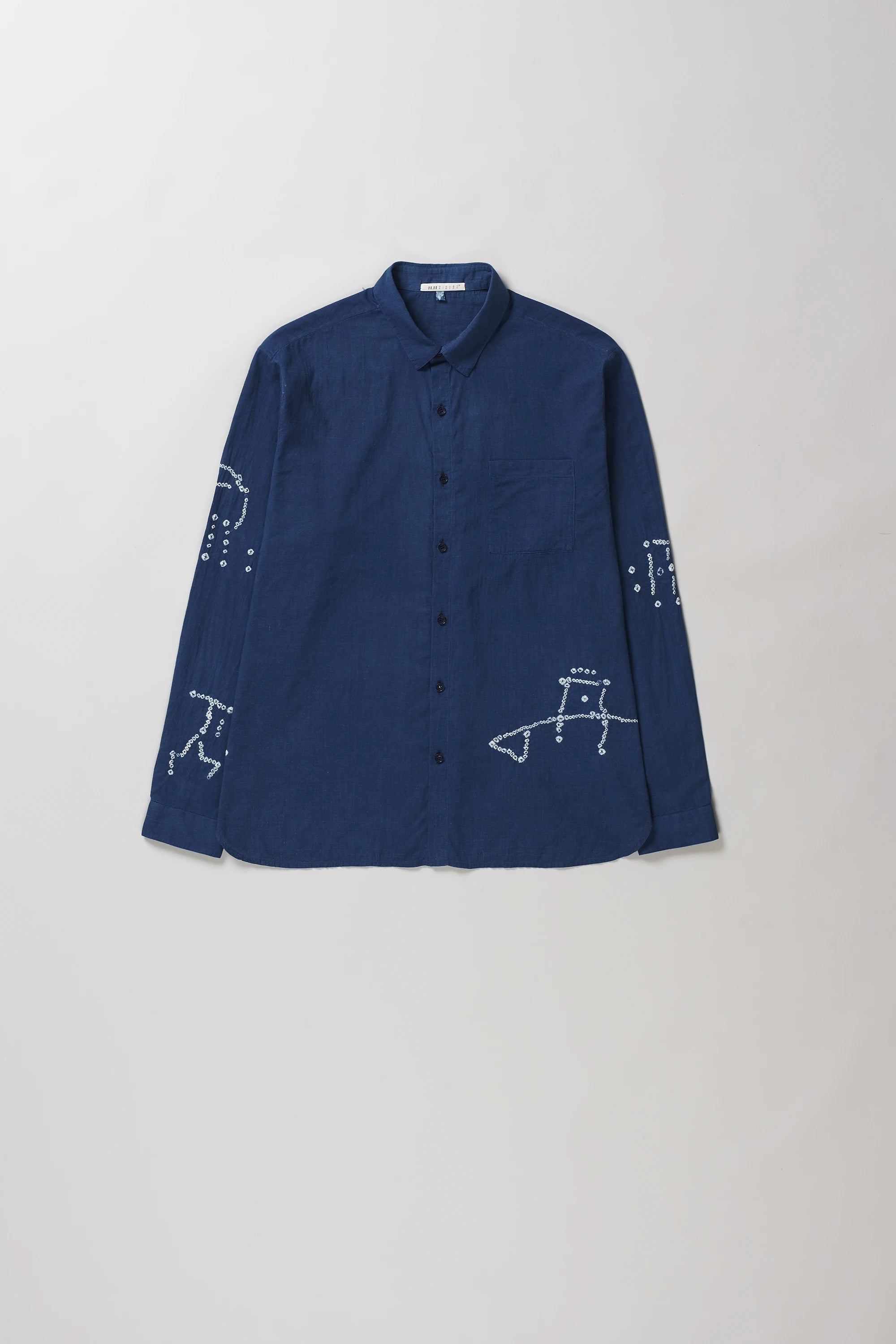 A medium indigo long-sleeve button-up shirt with bandhani, laid flat against a light grey background.