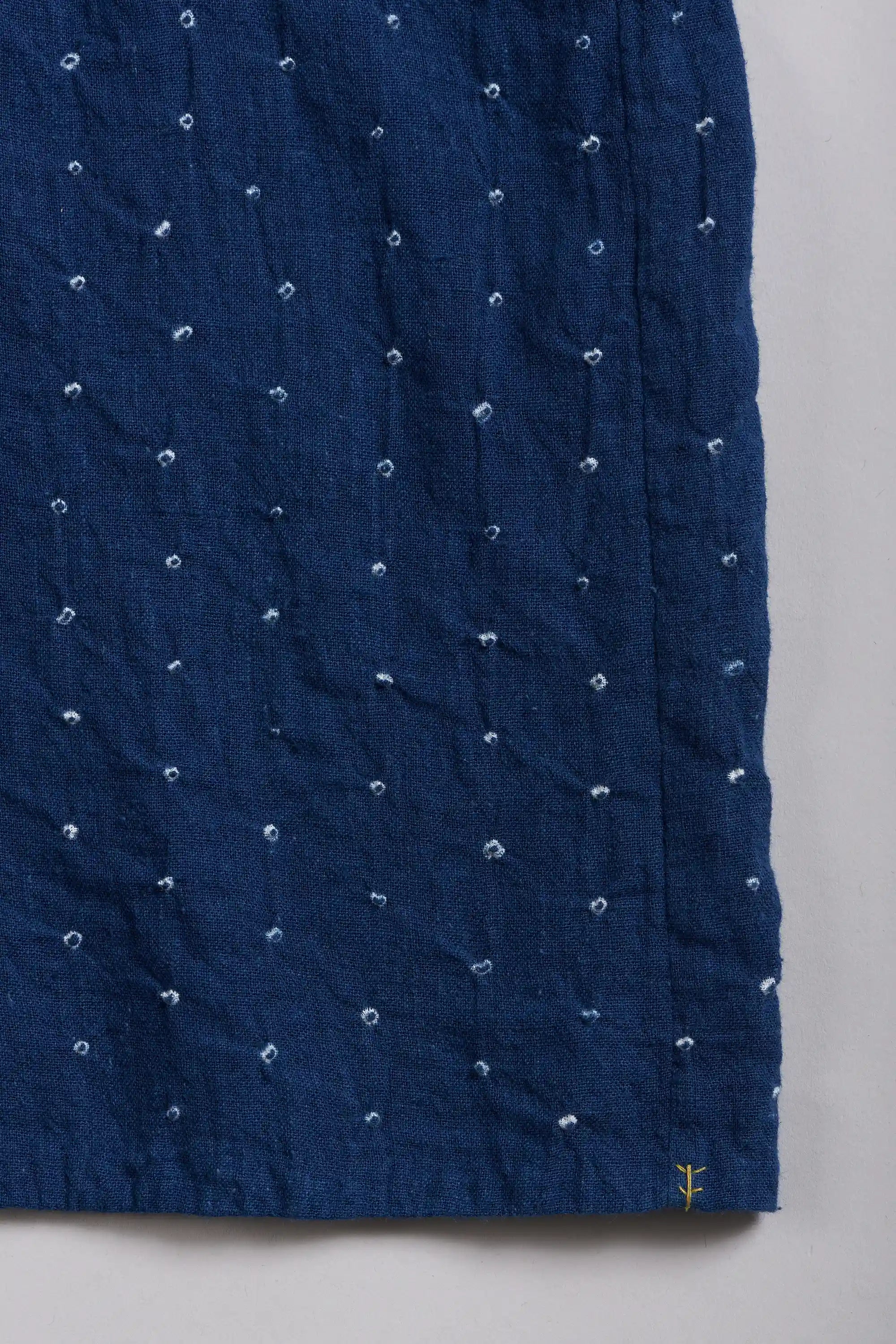 A close-up of a fabric with a small yellow hand detail near the bottom right corner.