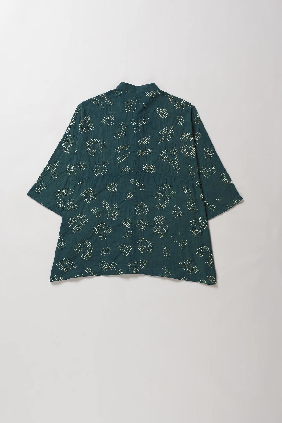 A bottle green kimono-style top with a light beige floral bandhani pattern, laid flat against a light grey background.