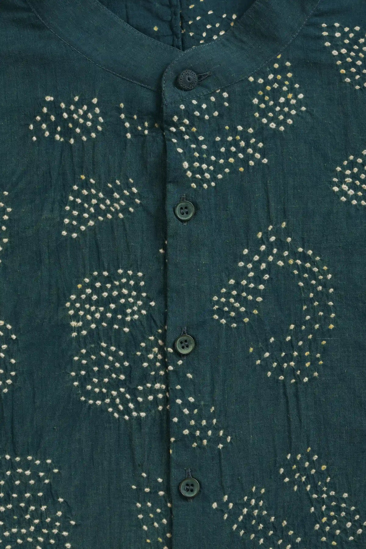 Close-up of a bottle green button-up shirt with white tie-dye bandhani patterns.
