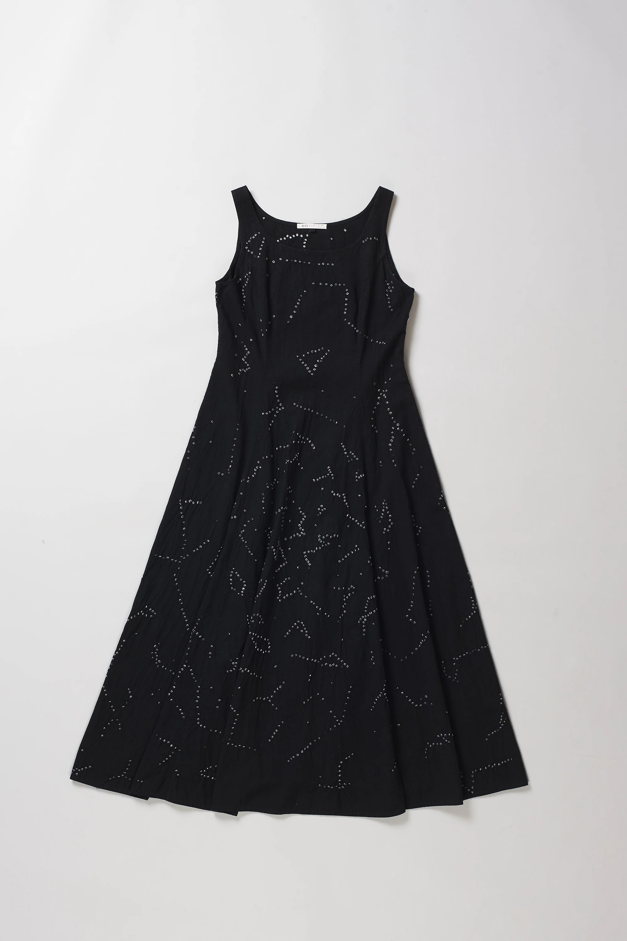 A sleeveless black A-line dress with a shibori pattern, displayed flat against a light grey background.