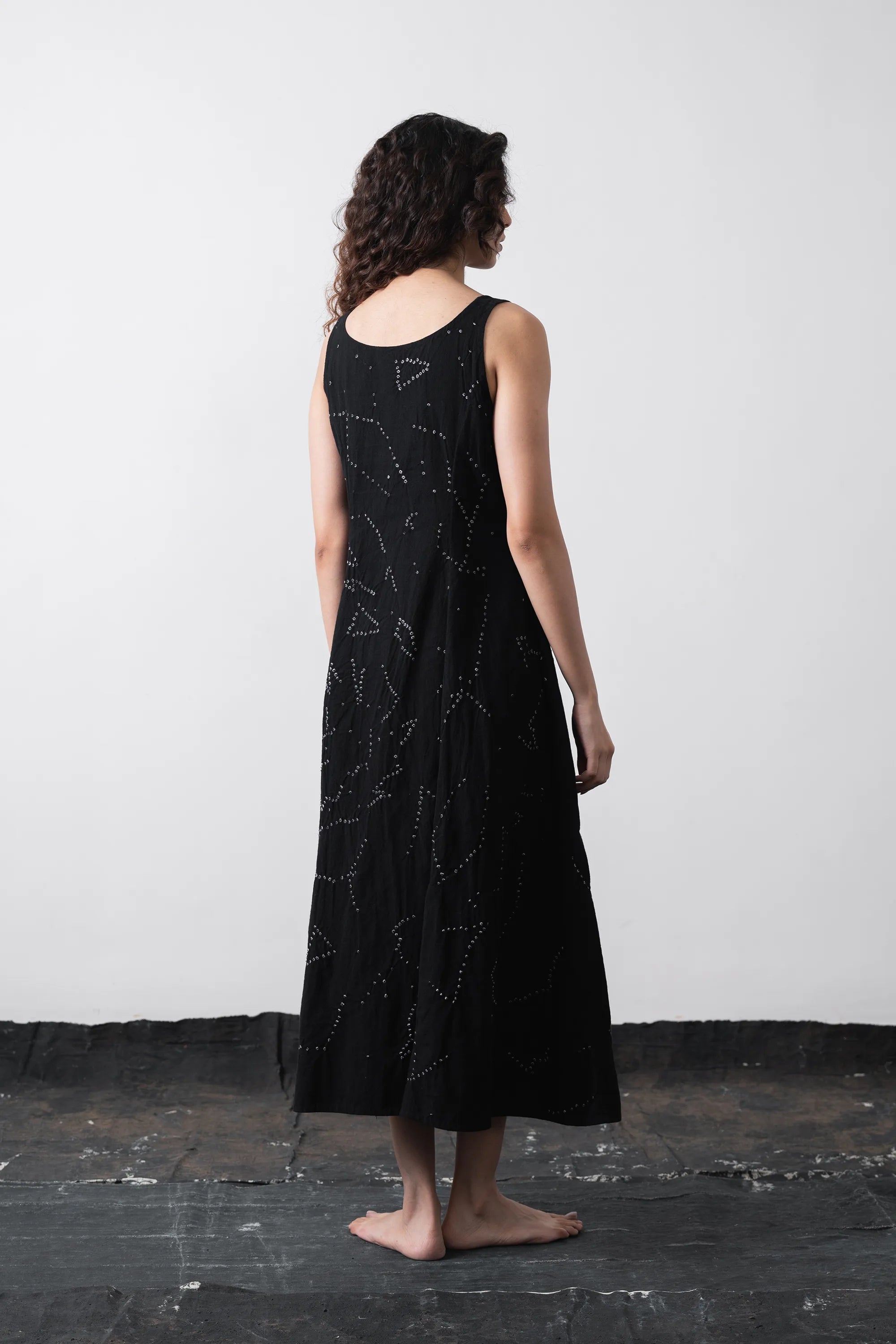 Back shot of model wearing a black long-sleeve kimono-style shirt with white dotted star patterns, paired with matching black pants, against a plain light grey background.