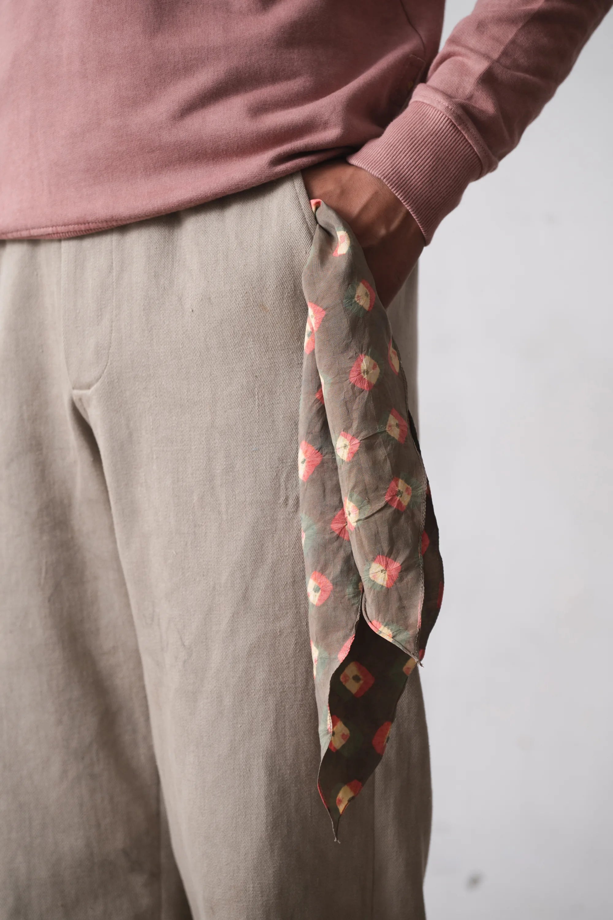 Person wearing a pink sweater and beige pants with a shibori scarf hanging out of the pocket