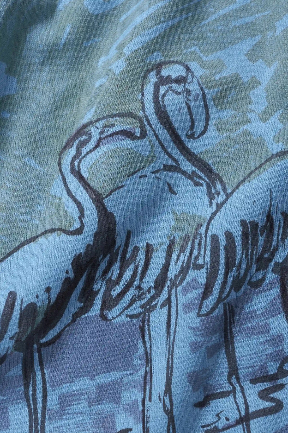 A close-up of a fabric surface featuring a stylized illustration of flamingos in dark navy outlines against a mottled blue and grey background.