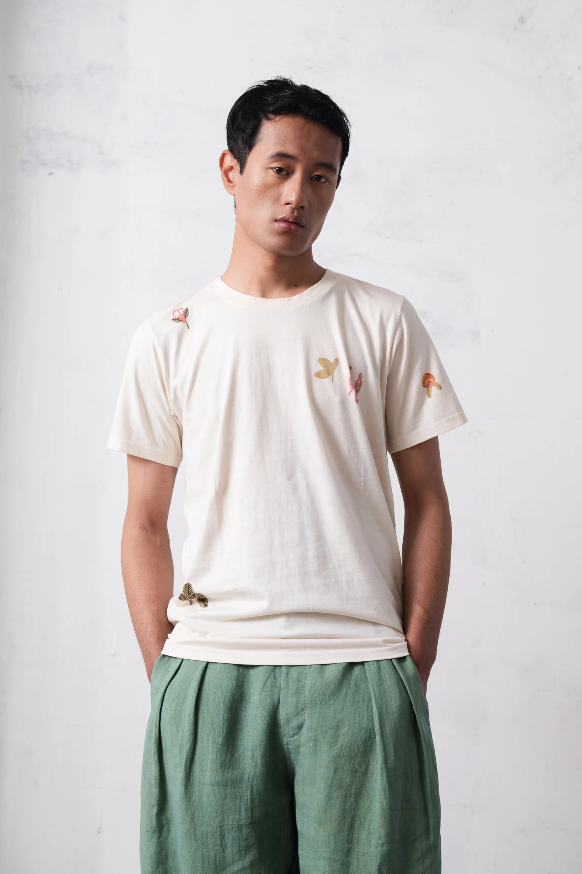 Man wearing a white t-shirt with hand paint on a light grey background