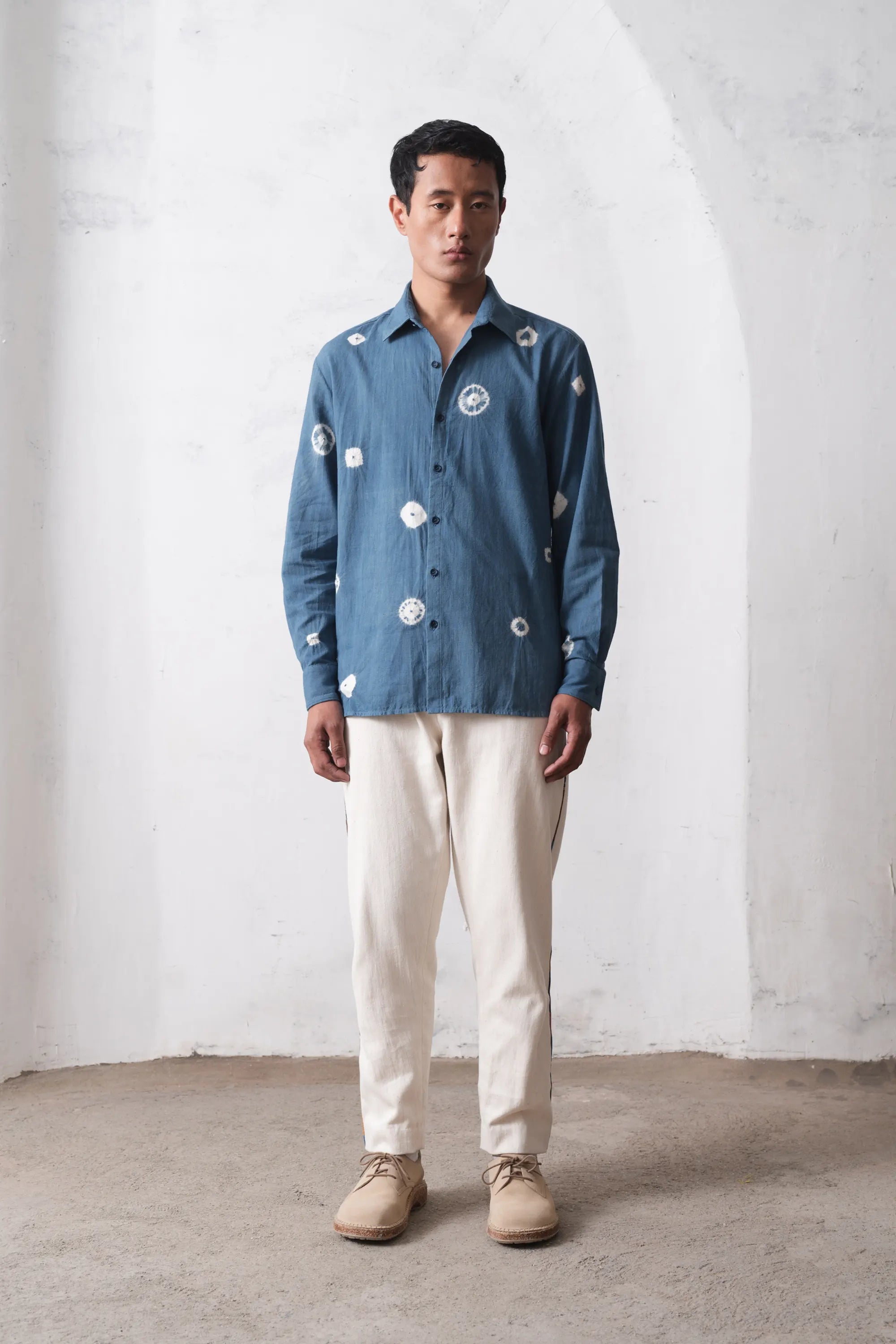 Man wearing a blue cotton shirt and ecru pants
