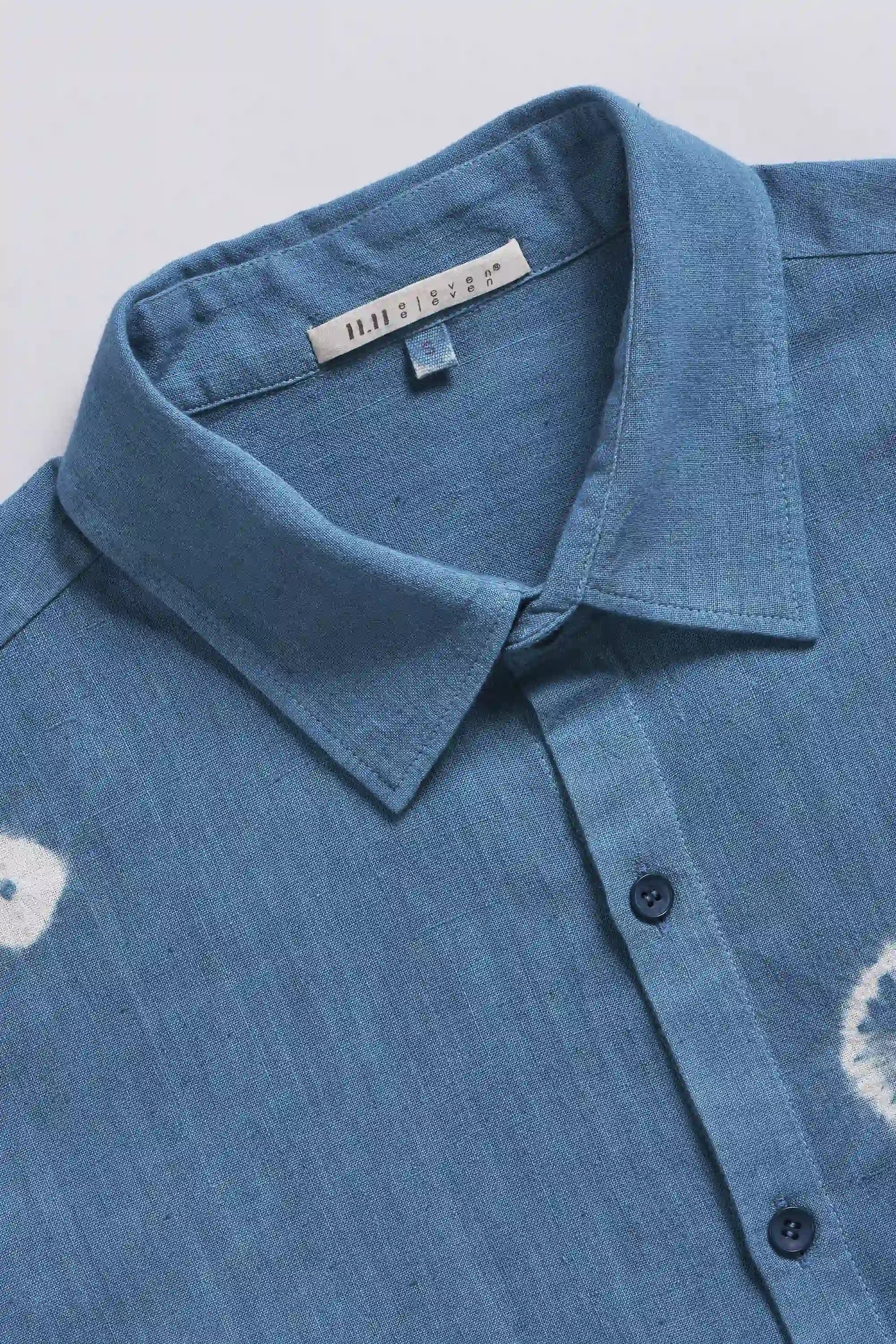 Close-up of a blue shirt with a collar and buttons on a light grey background