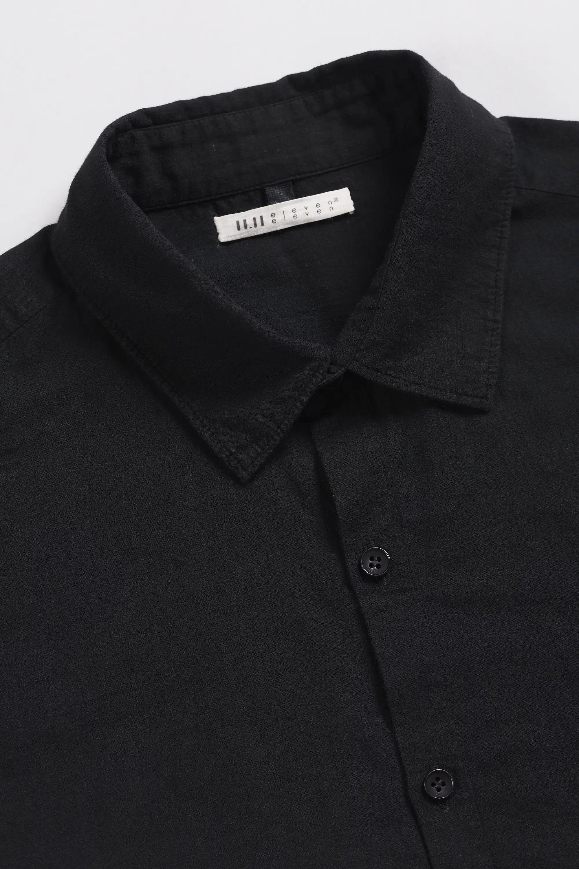 Close-up of a black button-down shirt collar with a visible white neck label.