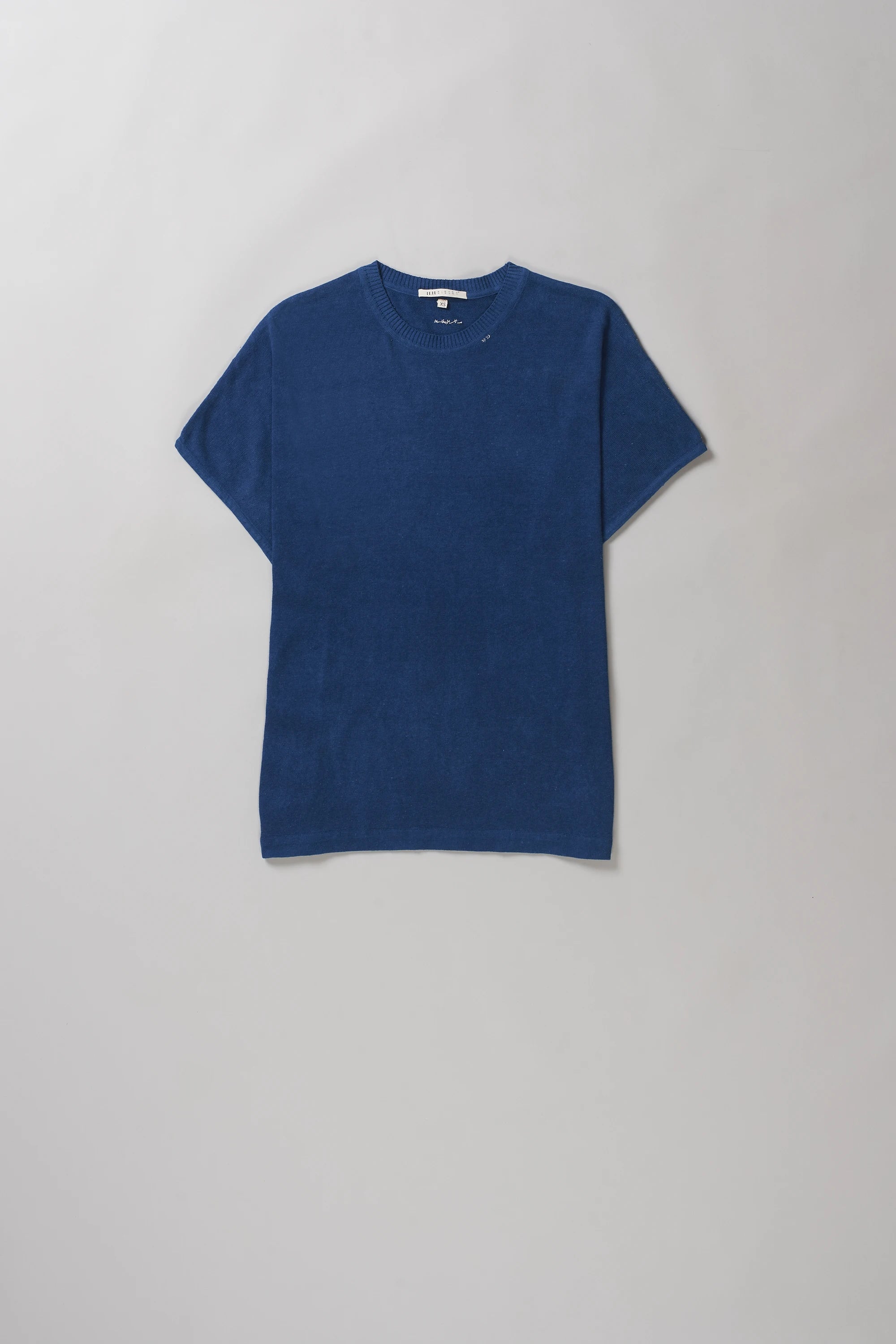 A solid medium indigo short-sleeve crewneck t-shirt laid flat against a light grey background.