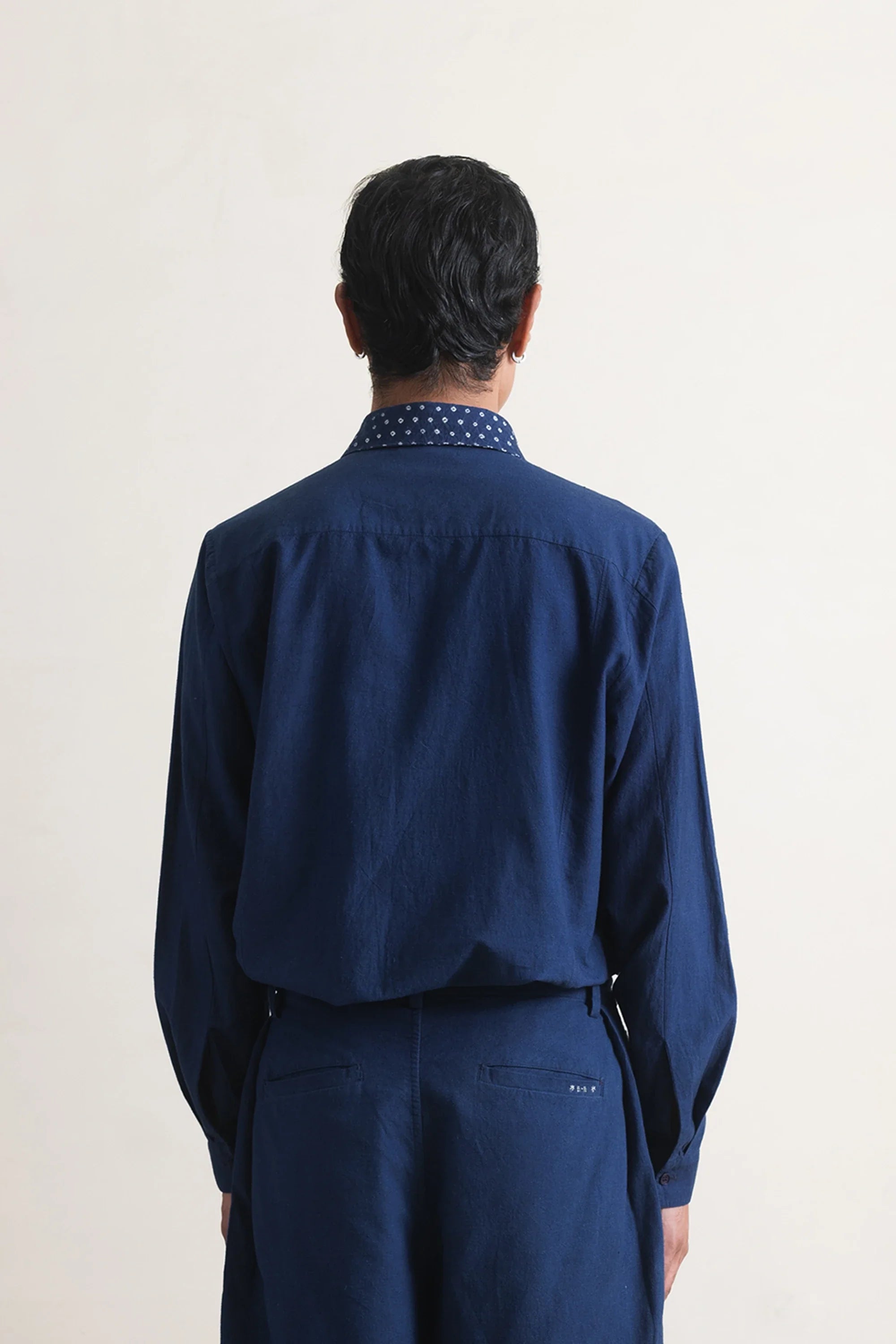 Man wearing a blue shirt and pants on a light grey background
