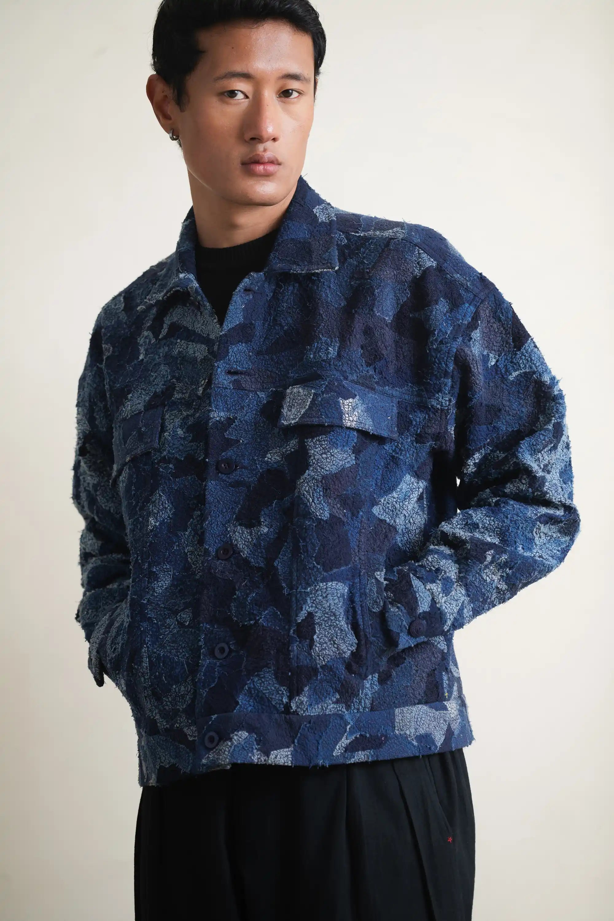 Person wearing a blue patchwork jacket against a light grey background