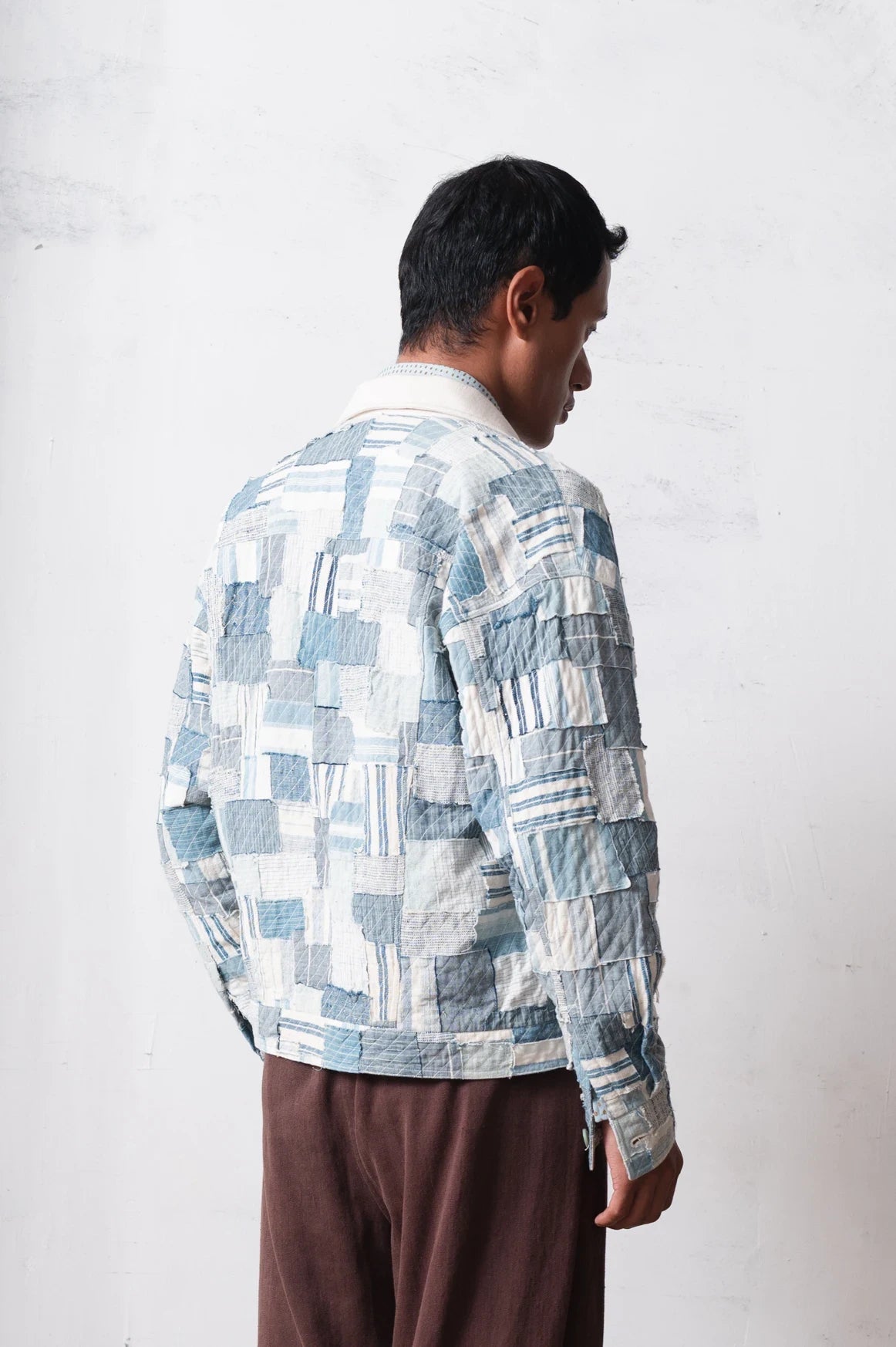 Person wearing a patchwork jacket with a light grey background