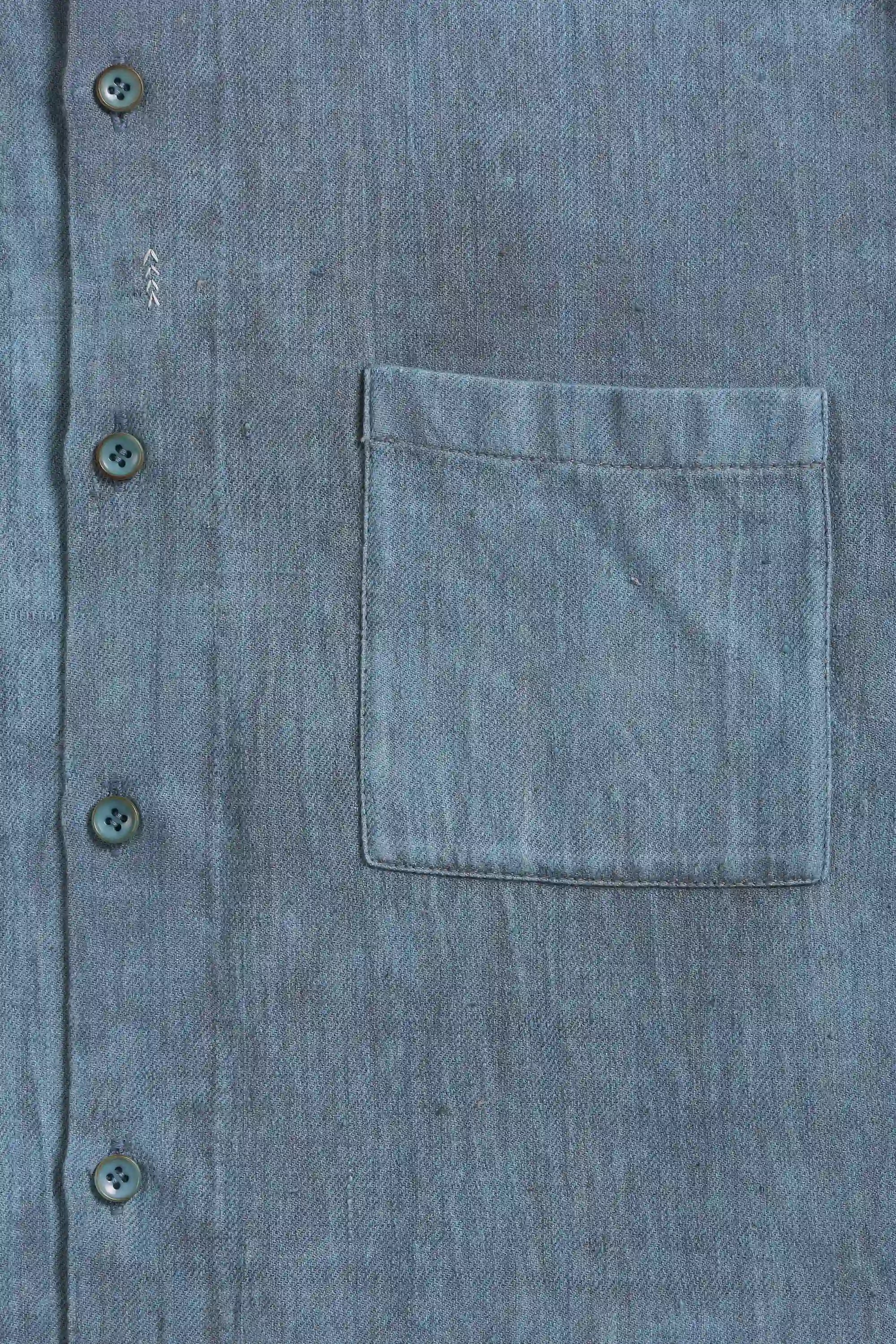 Close-up of a blue denim shirt with buttons and a pocket