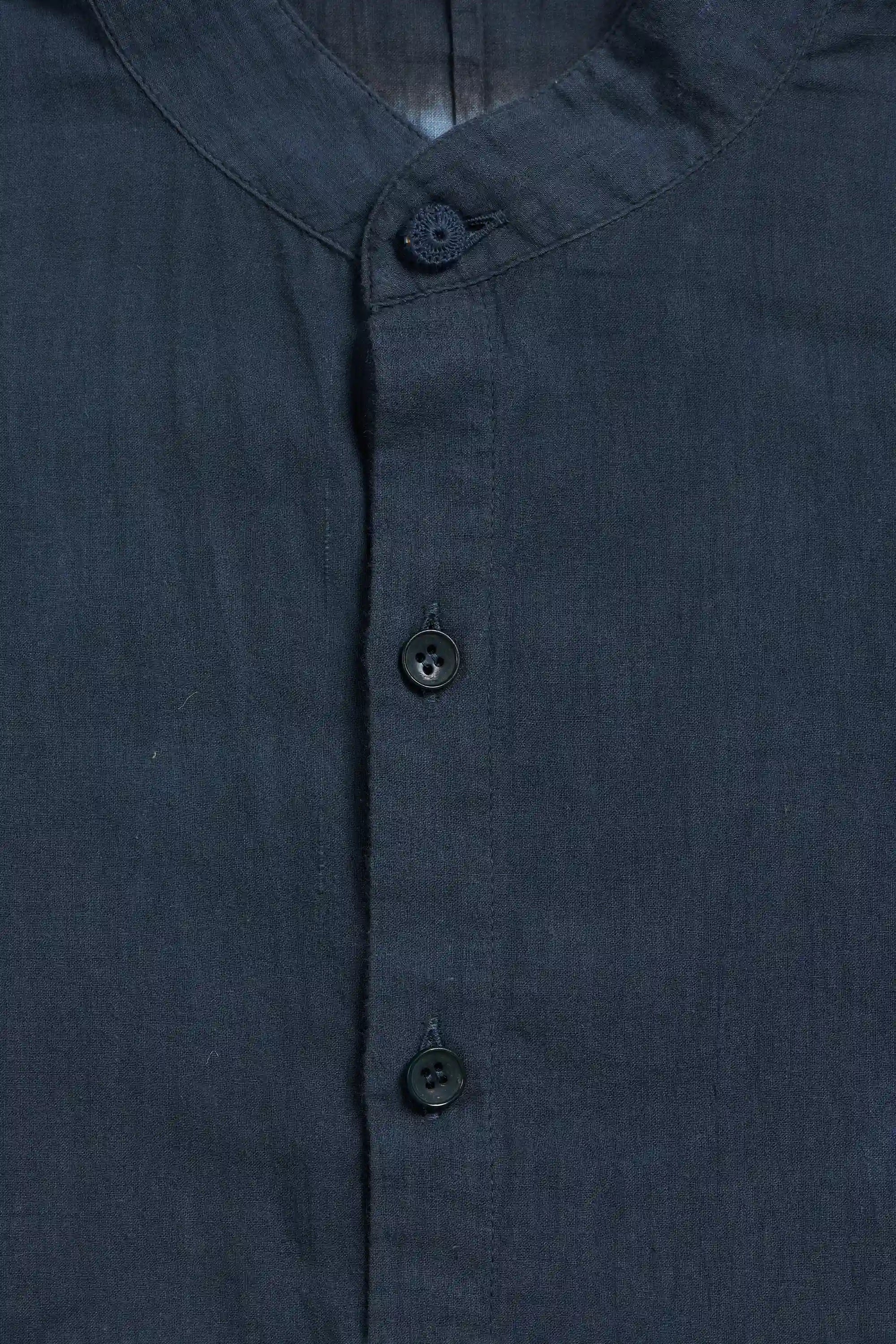 A close-up of a shirt with a collar and dark buttons.