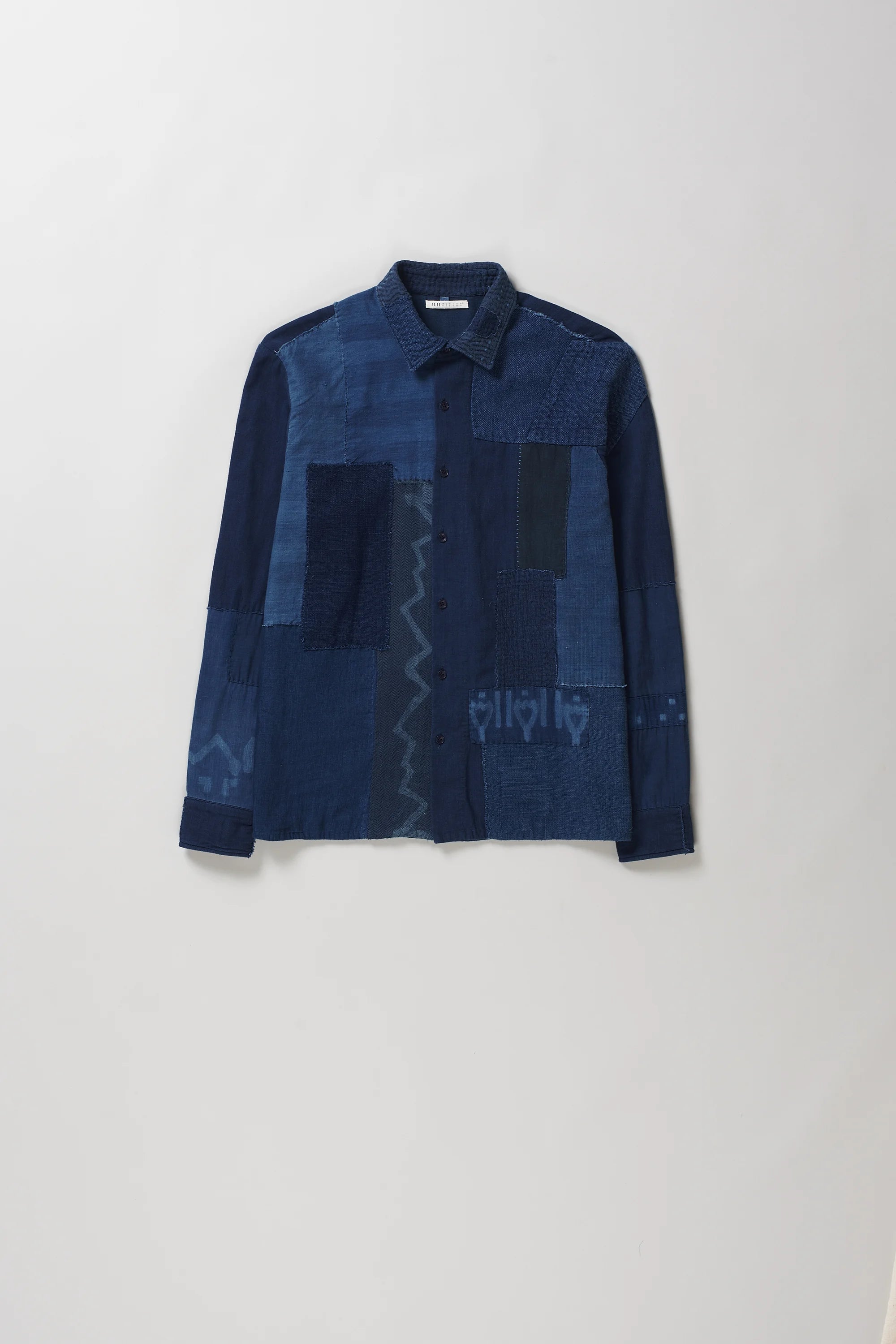 Front shot of long-sleeve button-up shirt with a dark blue patchwork design, displayed against a light grey background.