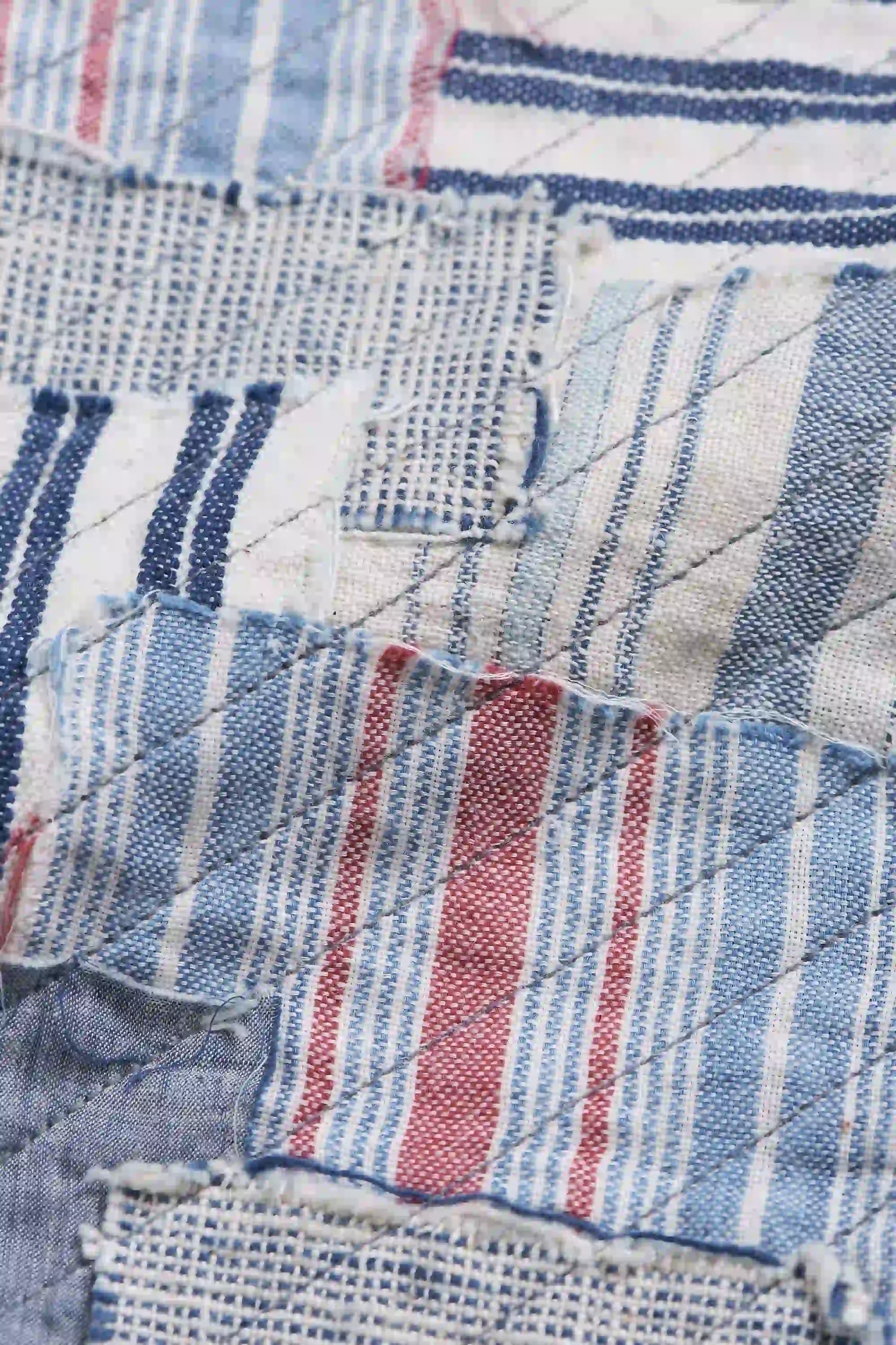 Close-up of a patchwork quilt with blue, white, and red fabric squares.