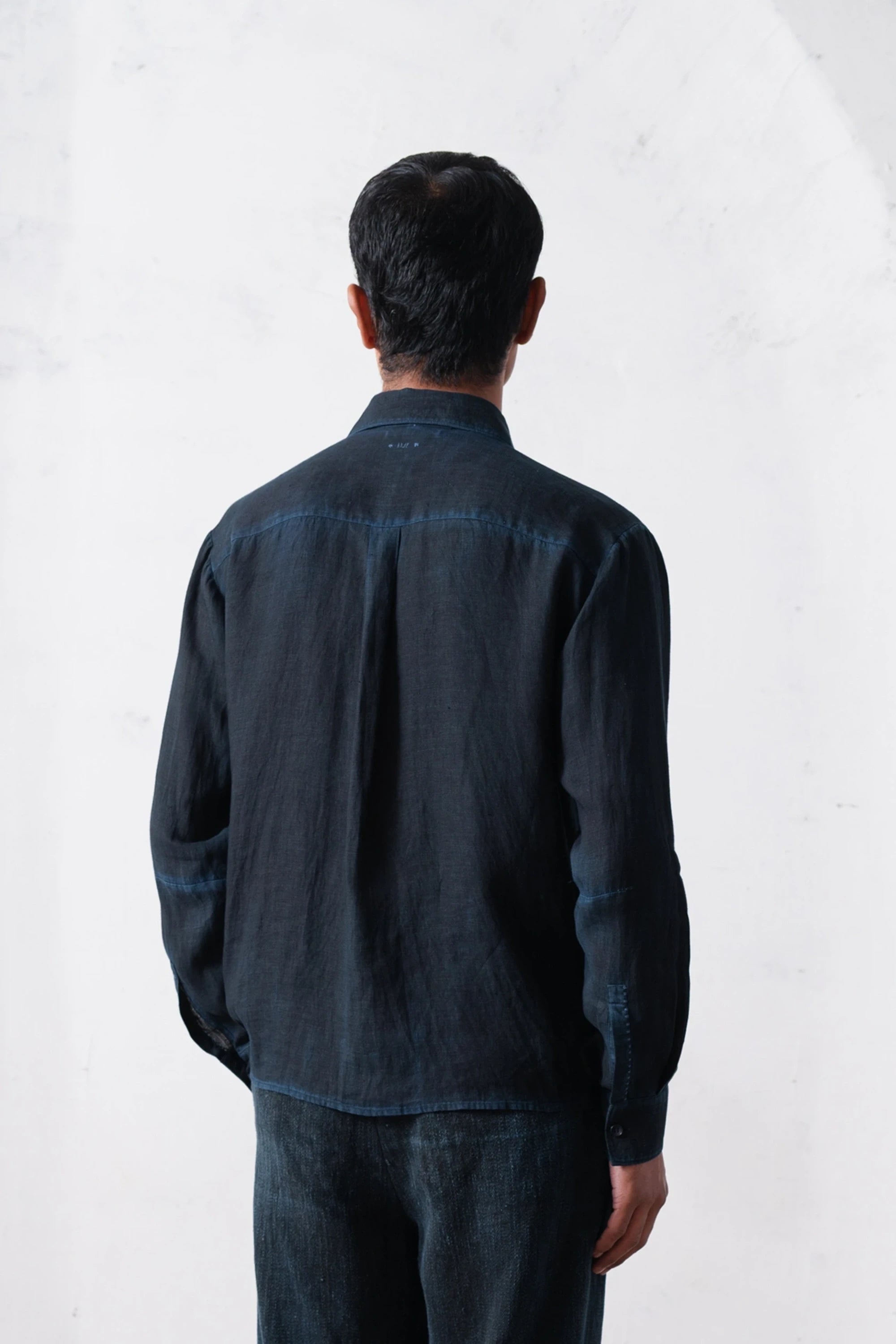 Back shot of a man wearing a black shirt and pants on a white background