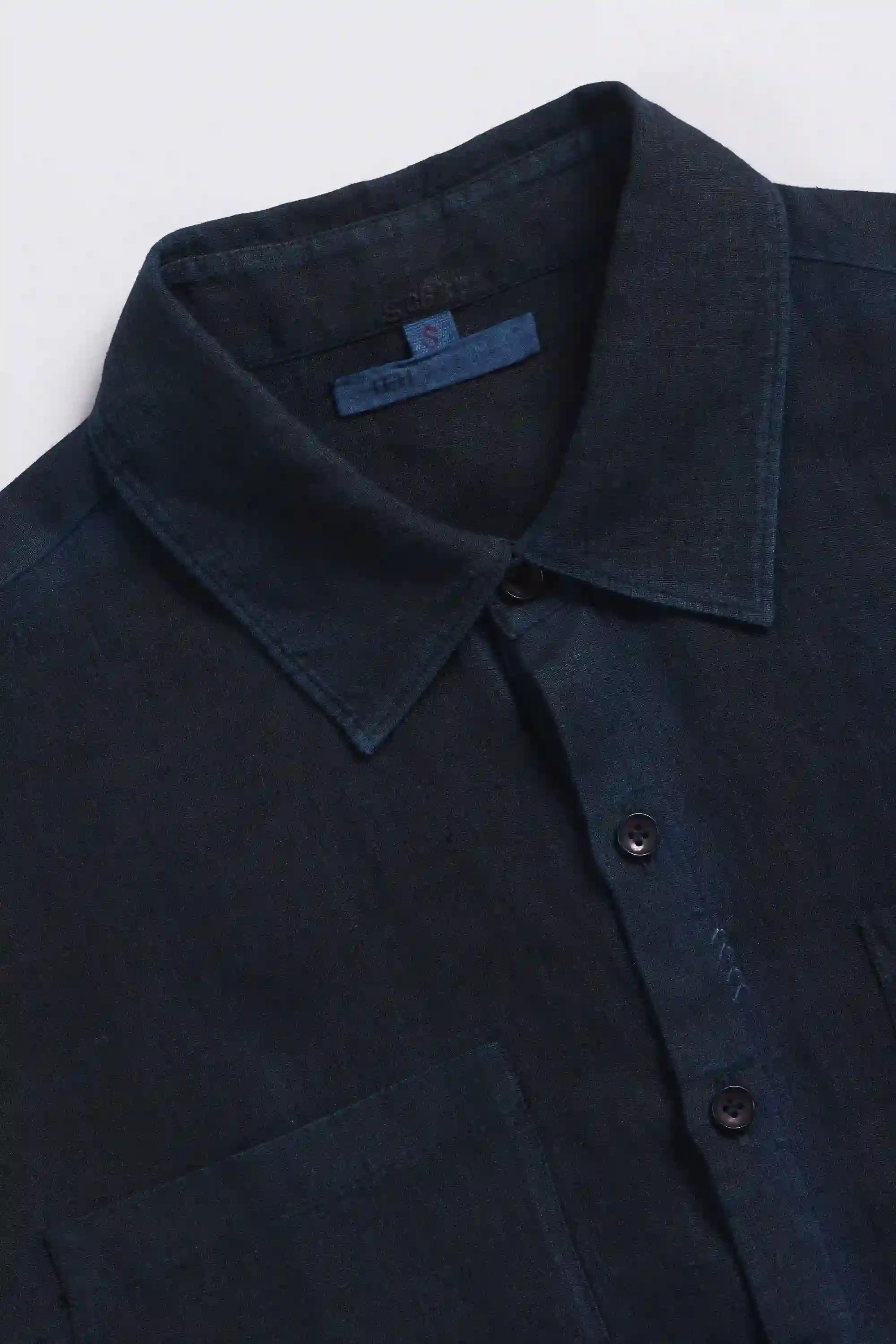 Close-up of a black shirt with collar and buttons on a white background